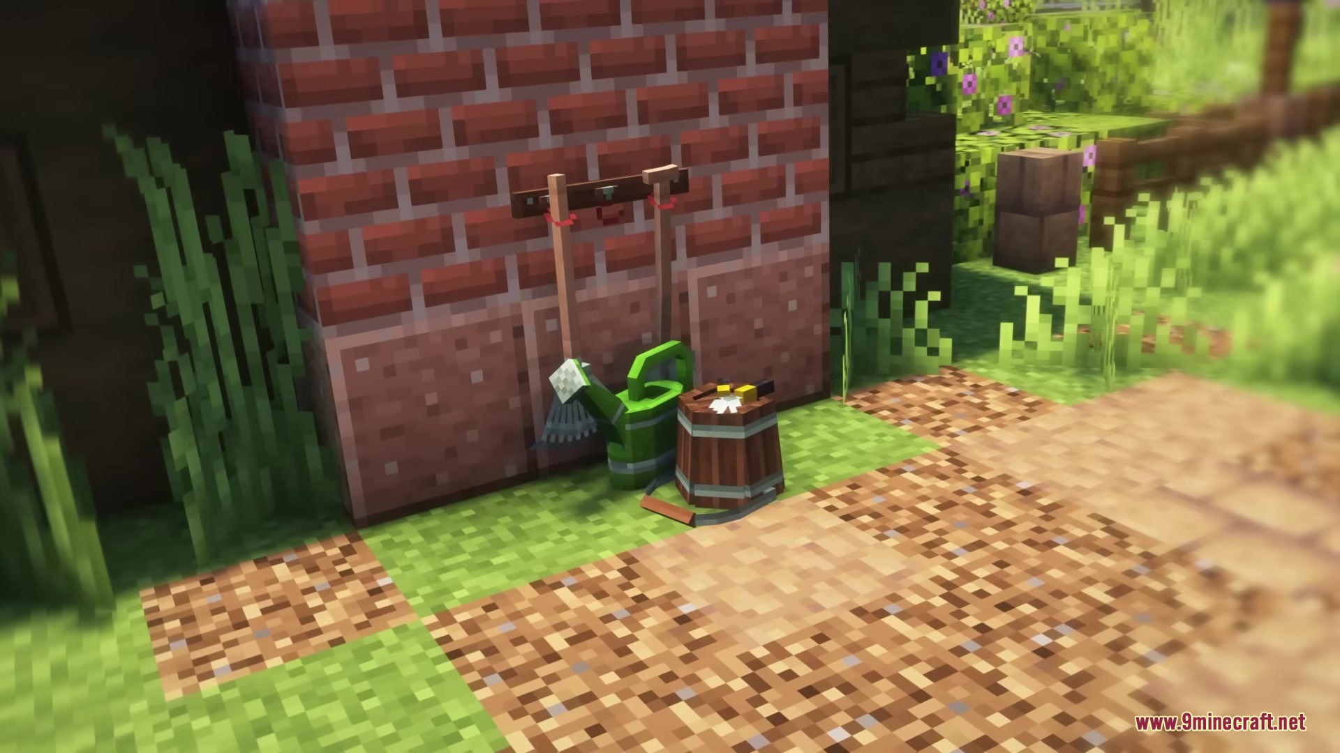 Various gardening tools and a watering can leaning against a red brick wall