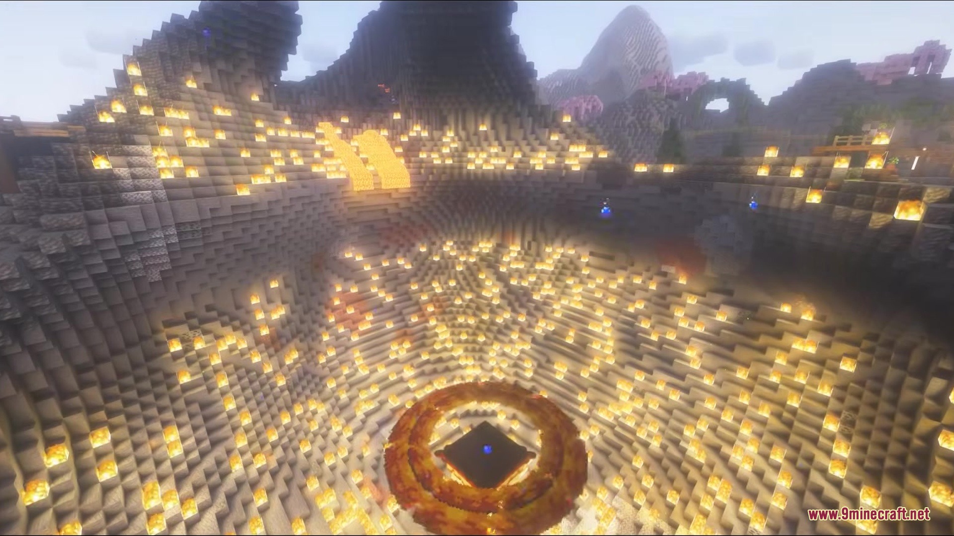 A massive crater lit by torches with a fiery ring at the center
