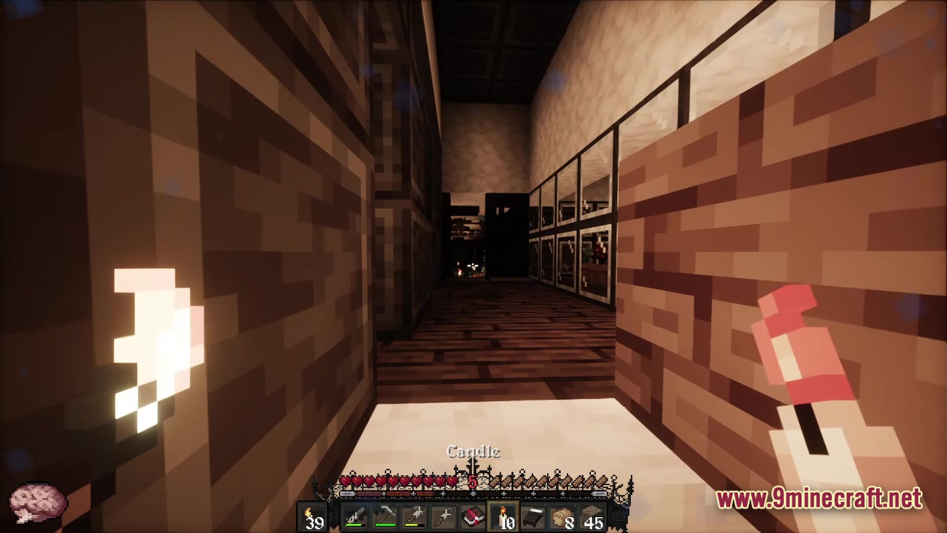 A player explores a dark interior hallway while holding a lit candle and a red item