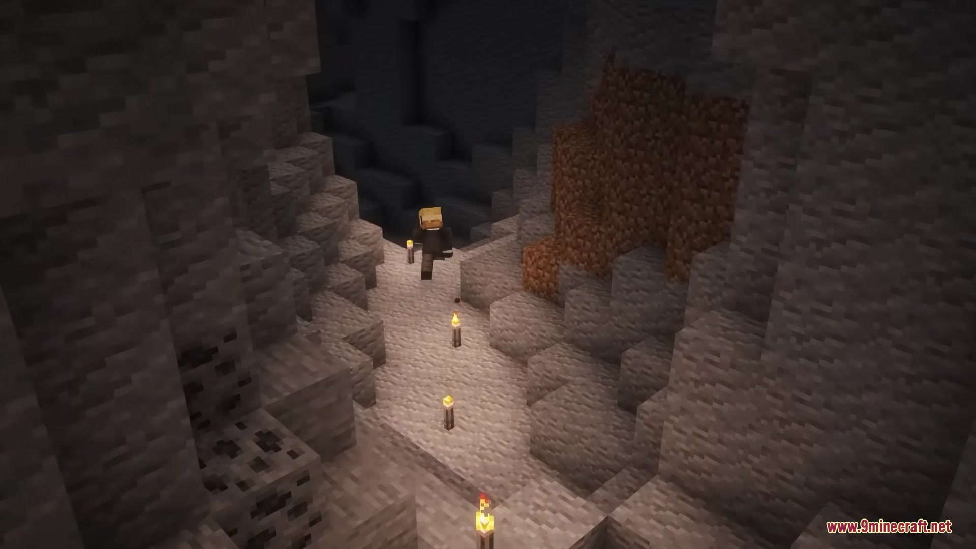 A player character exploring a dark cave lit by several flimsy torches