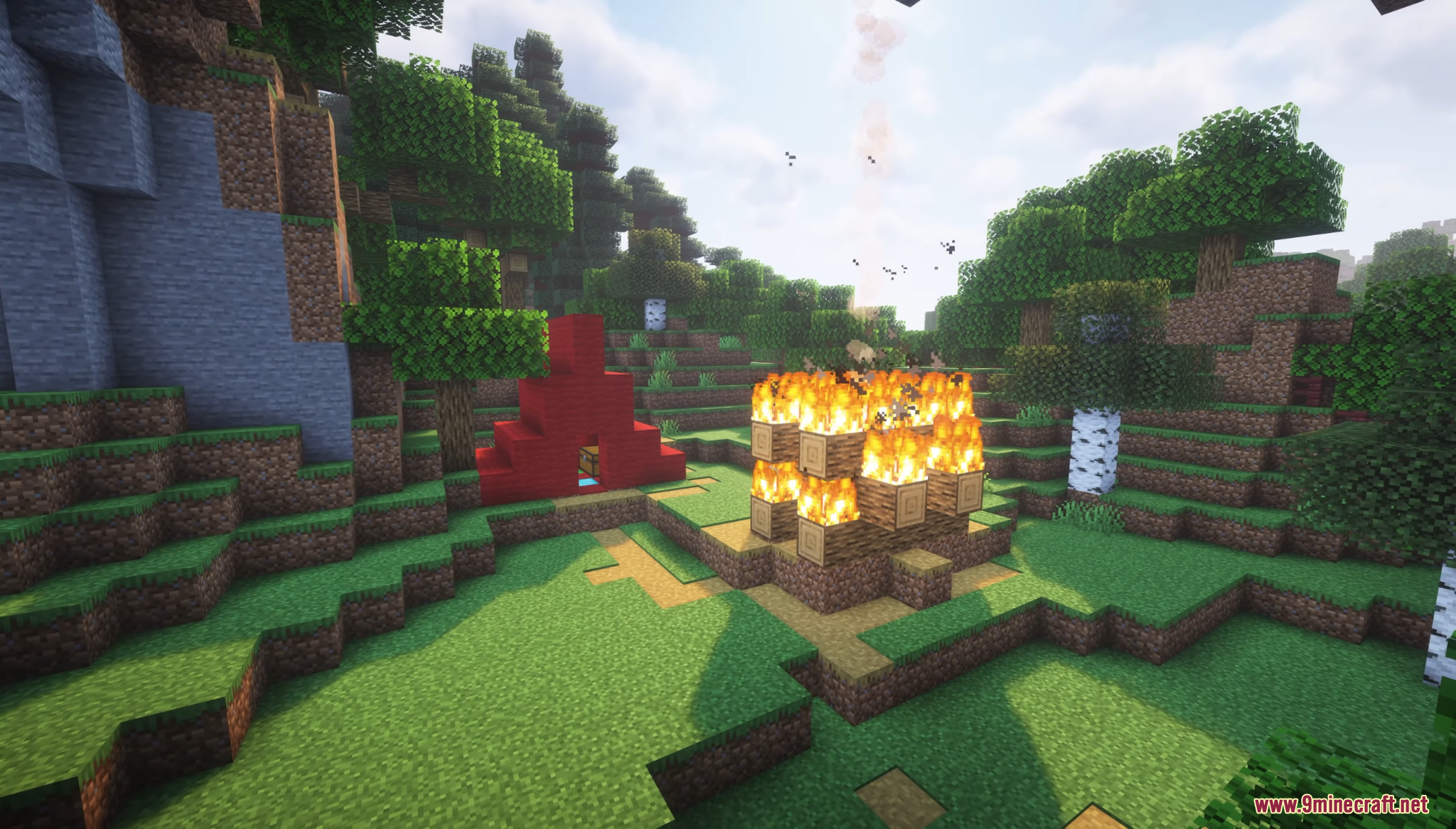 A large bonfire burns next to a red tent in the forest