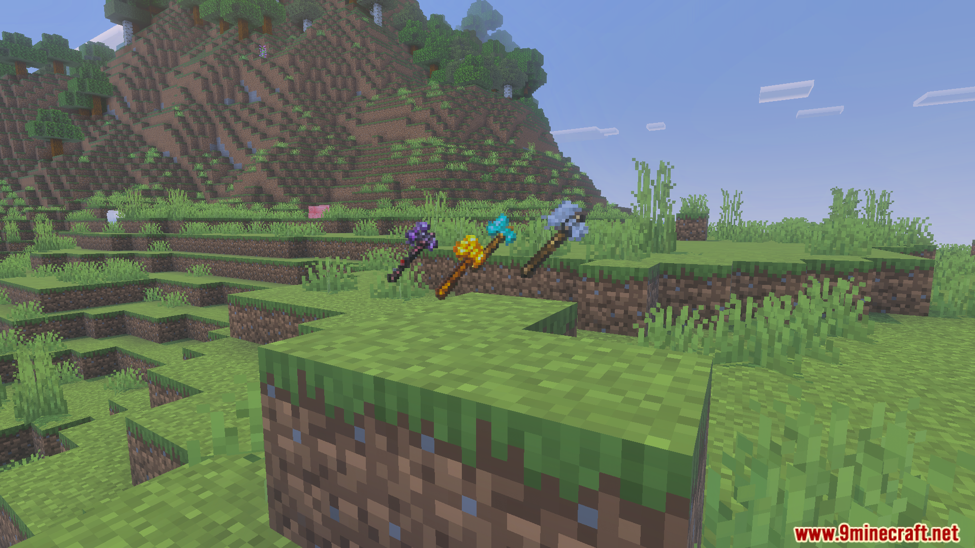 GHs Tree Capitator Addon Screenshot 8 Three colorful axes displayed on grass blocks in a green hilly landscape