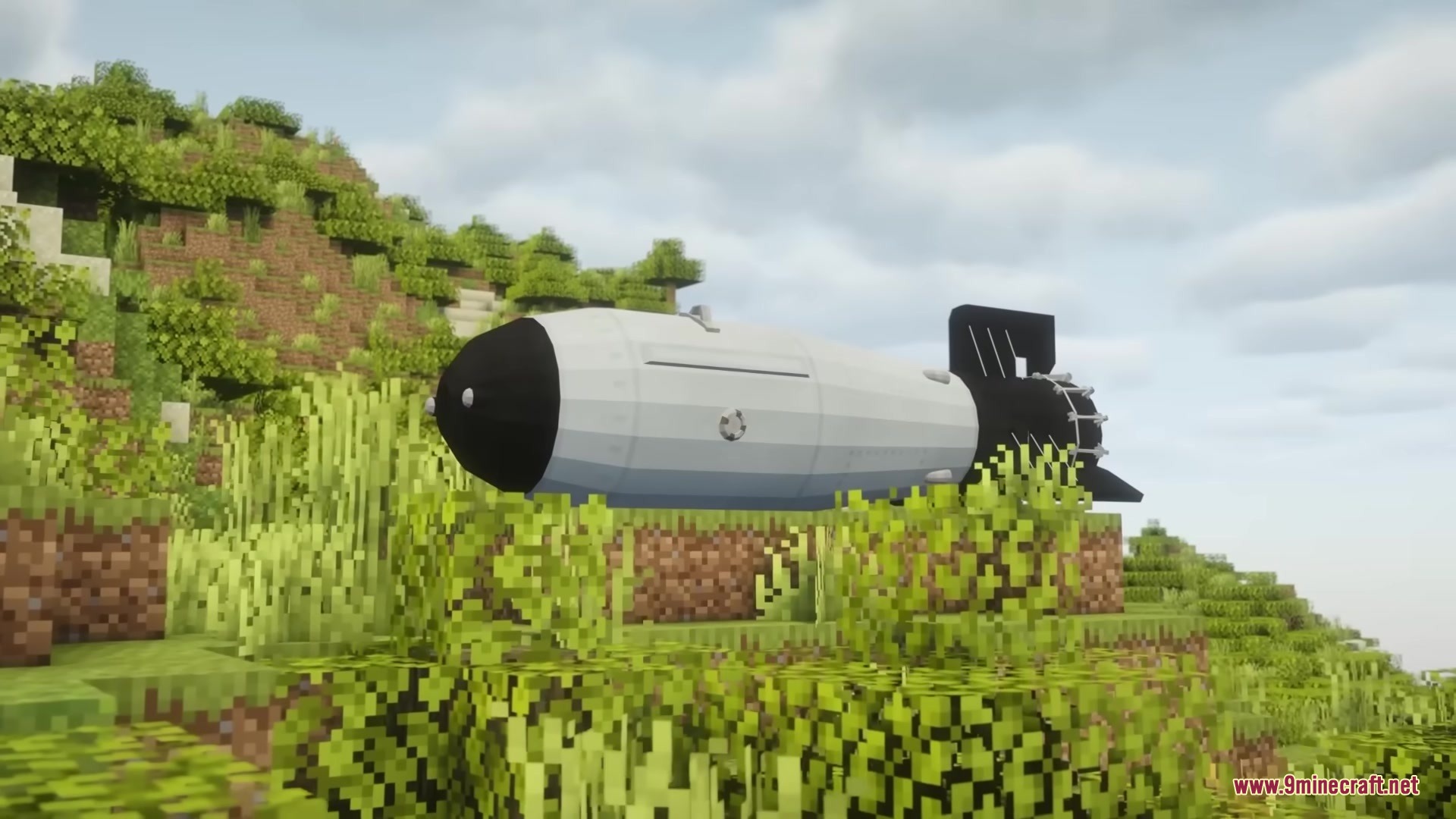 A massive white and black nuclear bomb resting on a grassy hill