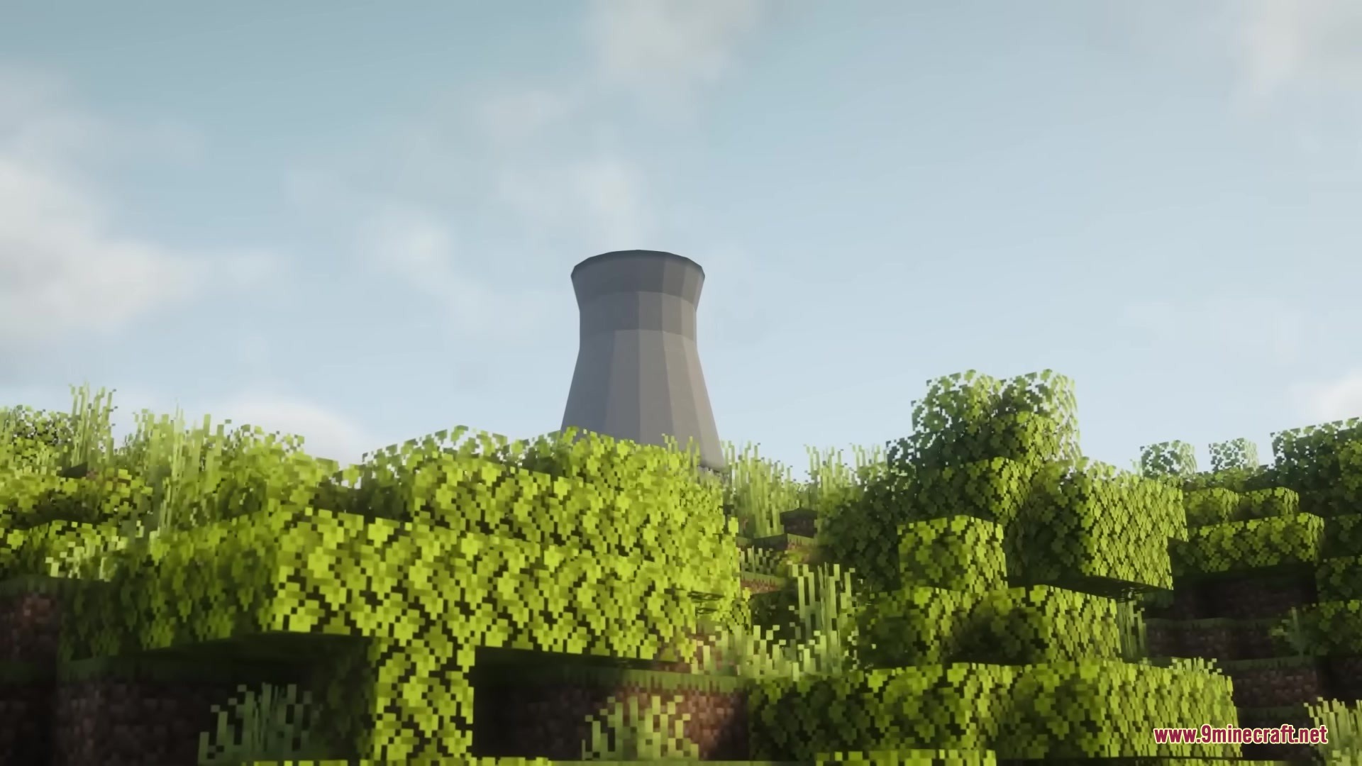 A tall grey cooling tower stands behind lush green trees in the distance