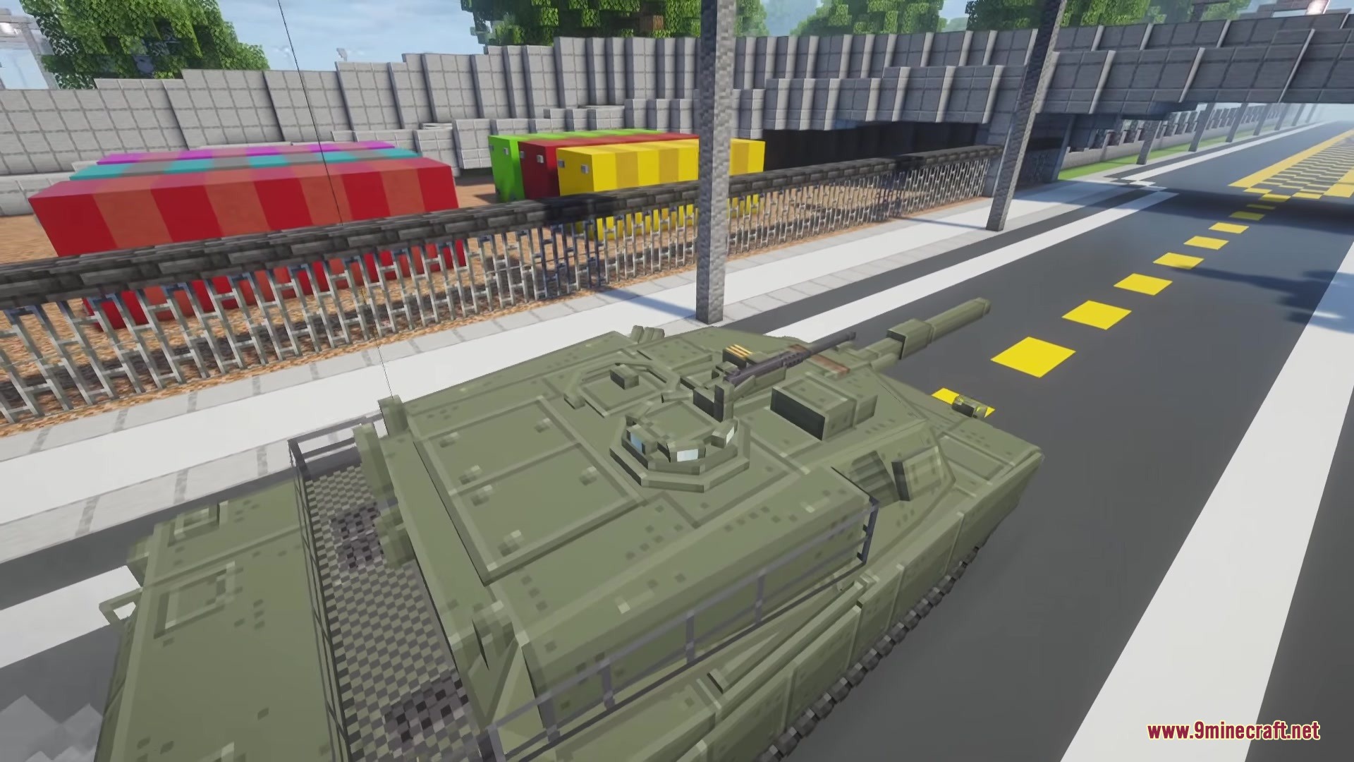 A green military tank parked on a road next to a metal fence