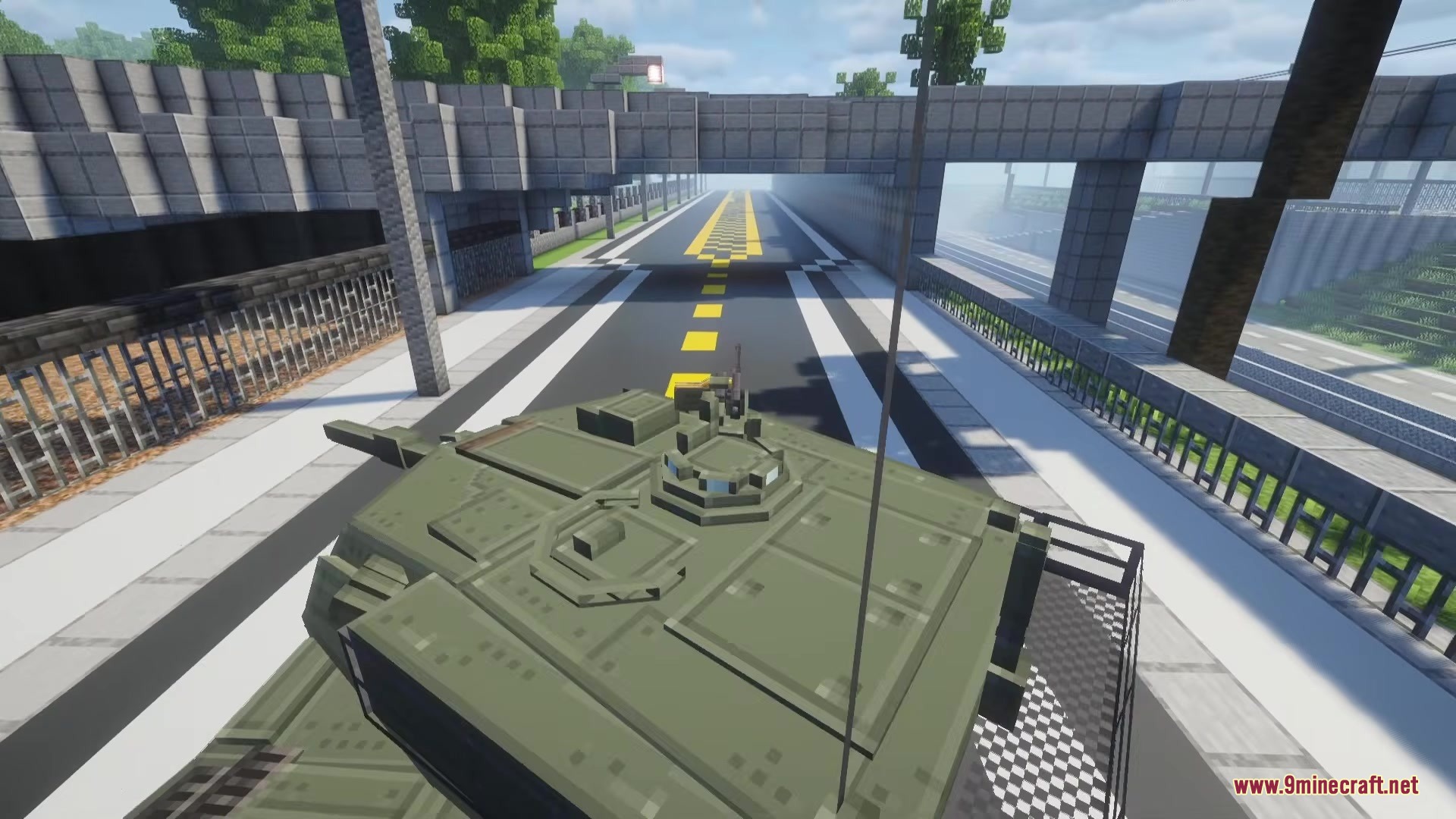Top view of a green tank driving on a road under a bridge