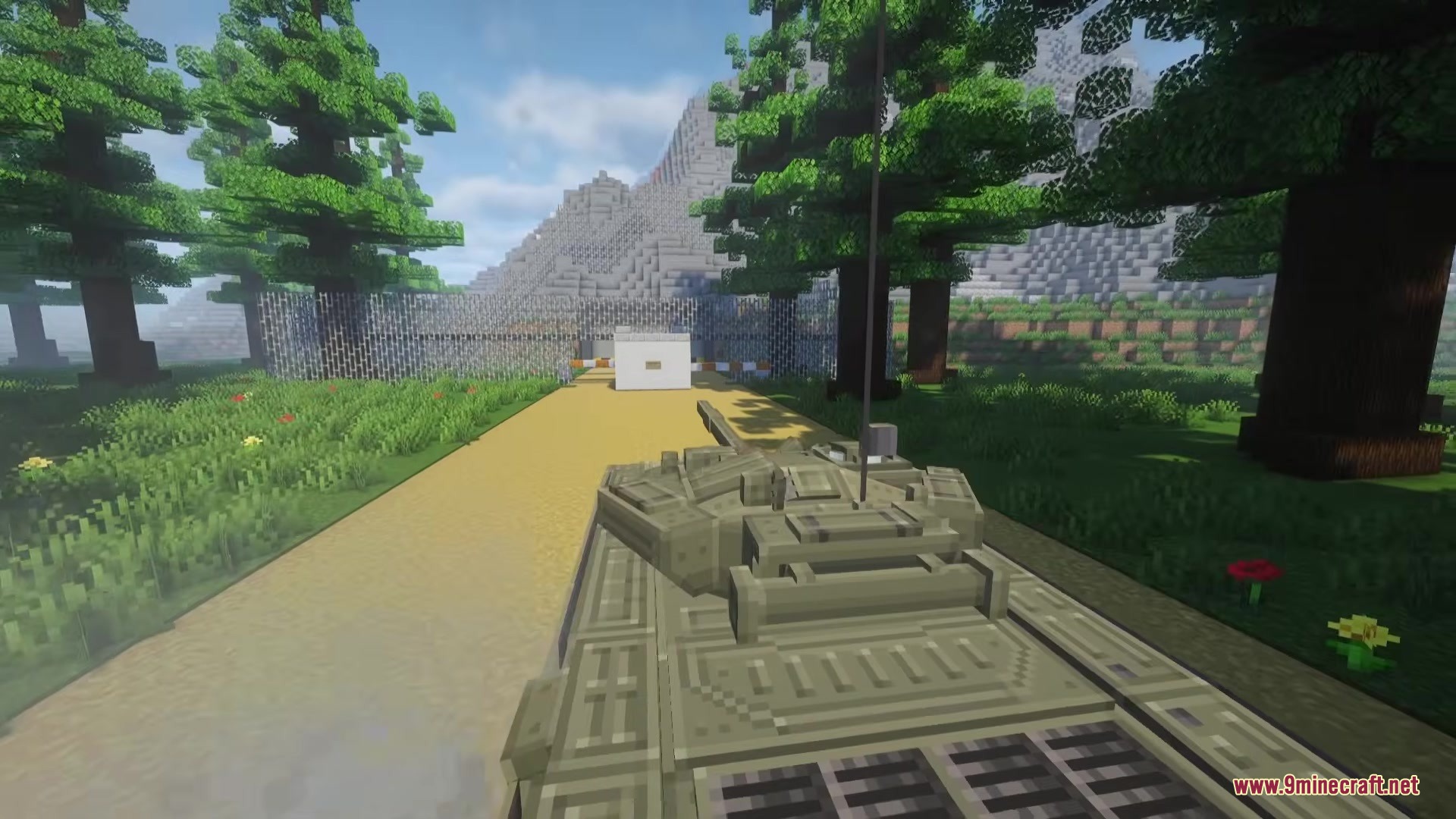 A detailed military tank driving through a forest with mountains in background
