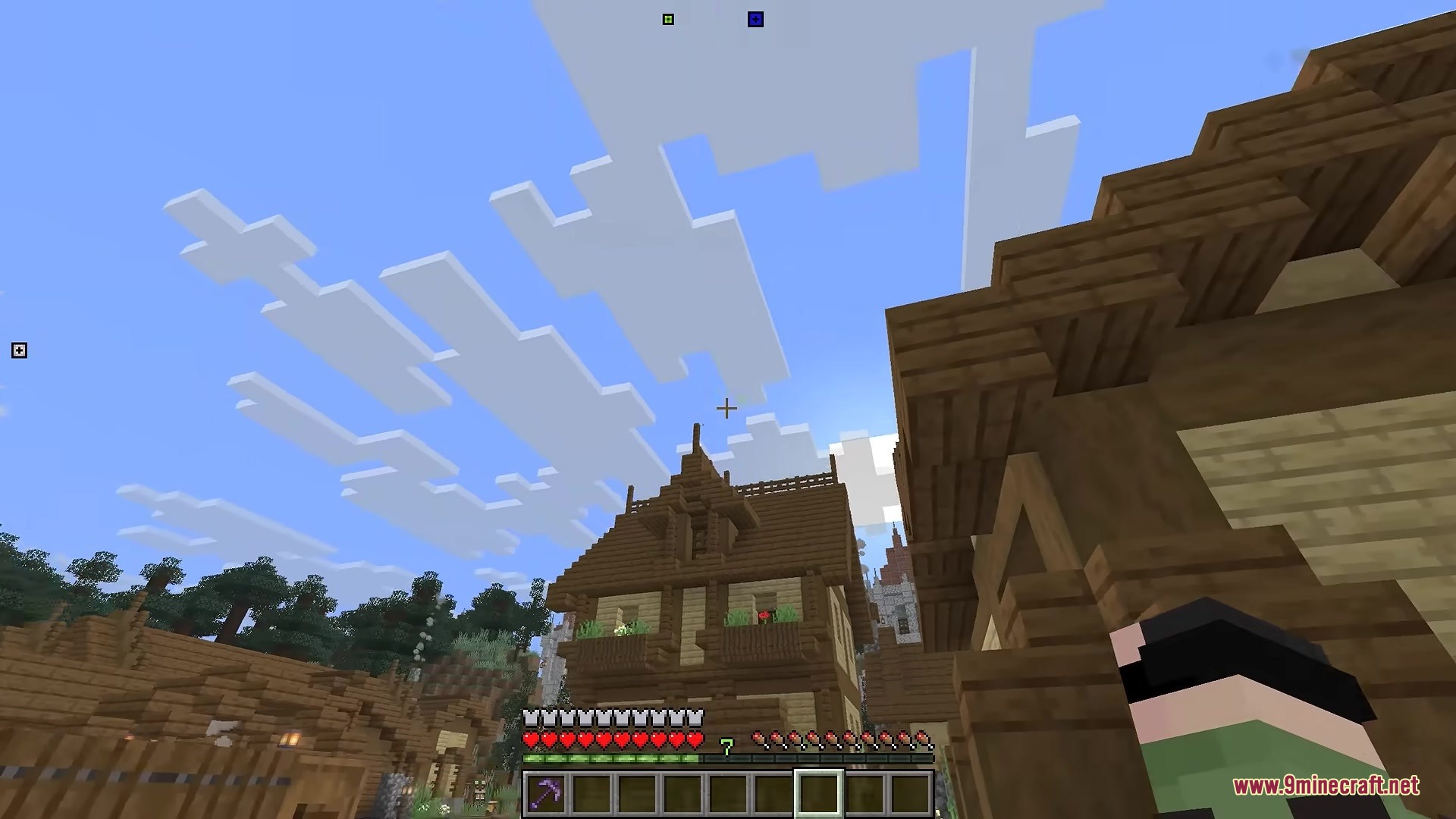 Player holding a pickaxe near a wooden house with markers on the border
