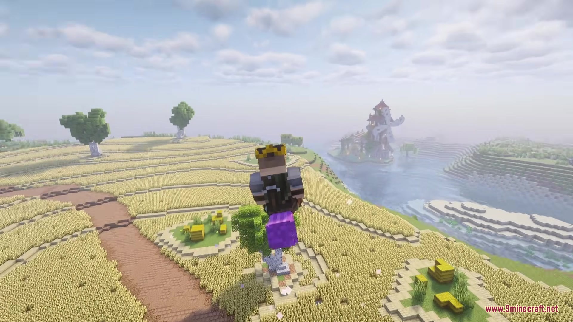 Magic Brooms Mod Screenshot 6 A player flies over a wheat field on a purple magical broom