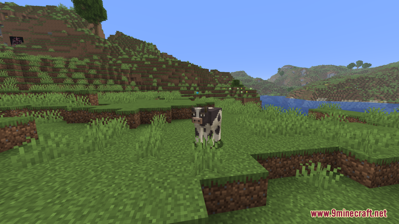 Mizuno's Cow Variants Resource Pack Screenshot 2 A spotted cow standing in a grassy field near a river and mountains