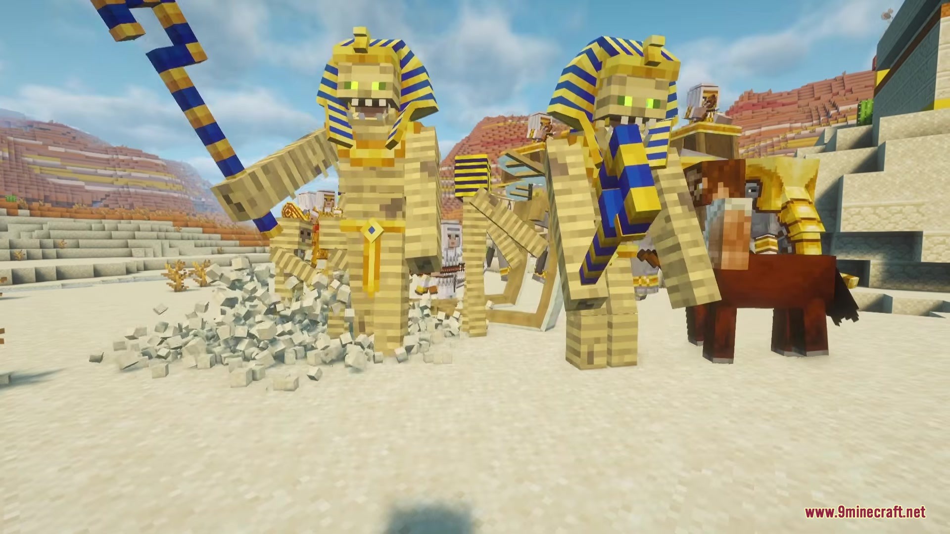 Two giant pharaoh mobs with golden staffs standing in a sandy desert