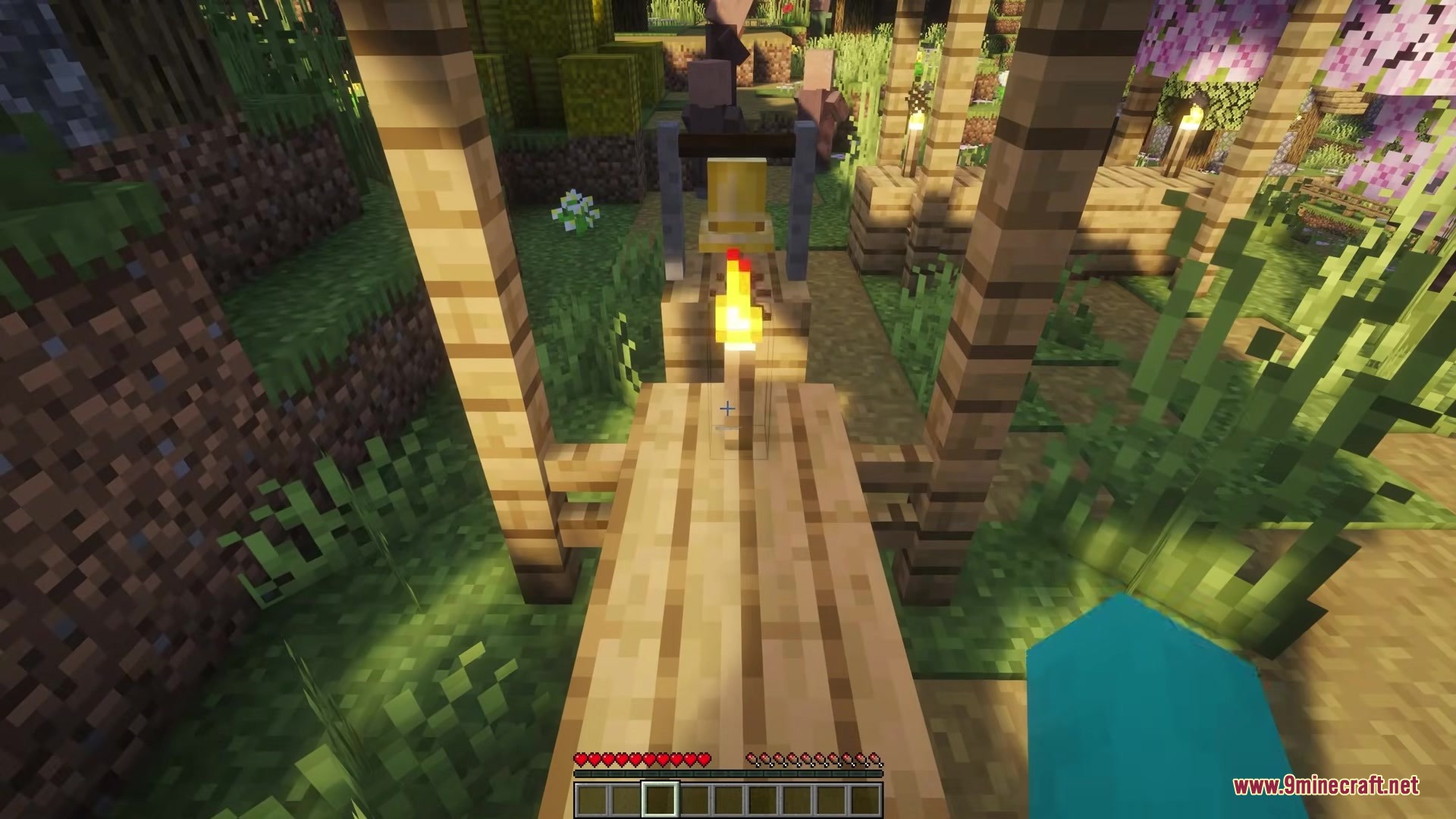 Picker Upper Mod Screenshot 7 A player approaches a lit torch on a wooden path in a village