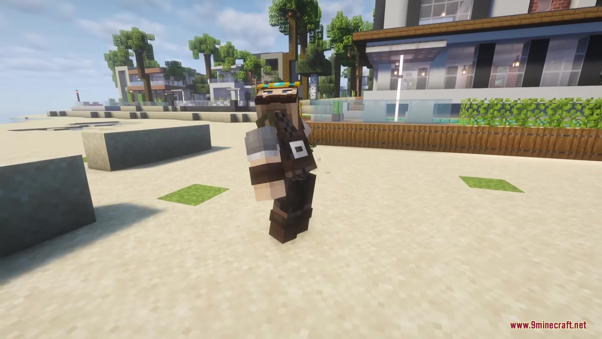 A Minecraft player character standing on a sandy beach near a modern house