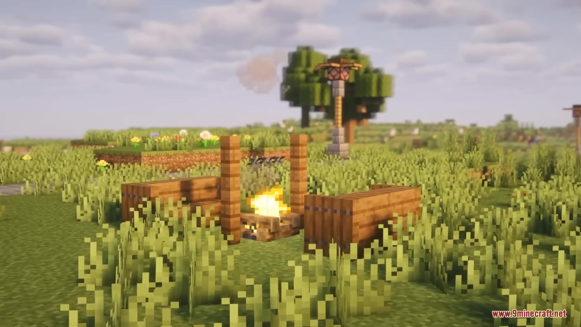 A campfire area with wooden benches and a lamp post in a field