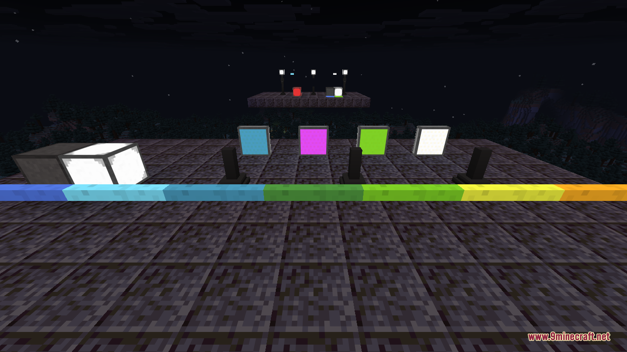 A row of small square illuminant panels in light blue, magenta, lime, and white, each mounted upright on a short post, with a colourful edge-light strip running across the floor in front of them