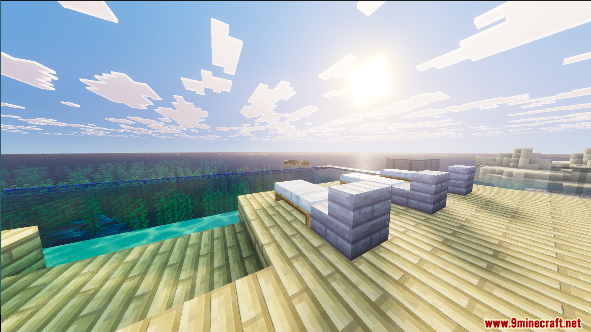 White lounge chairs on a wooden deck next to a glass swimming pool