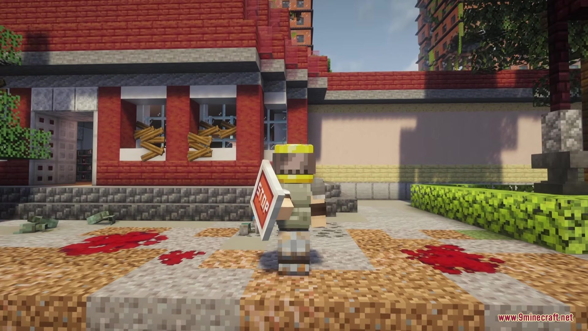 A survivor stands with a stop sign shield outside a boarded brick building