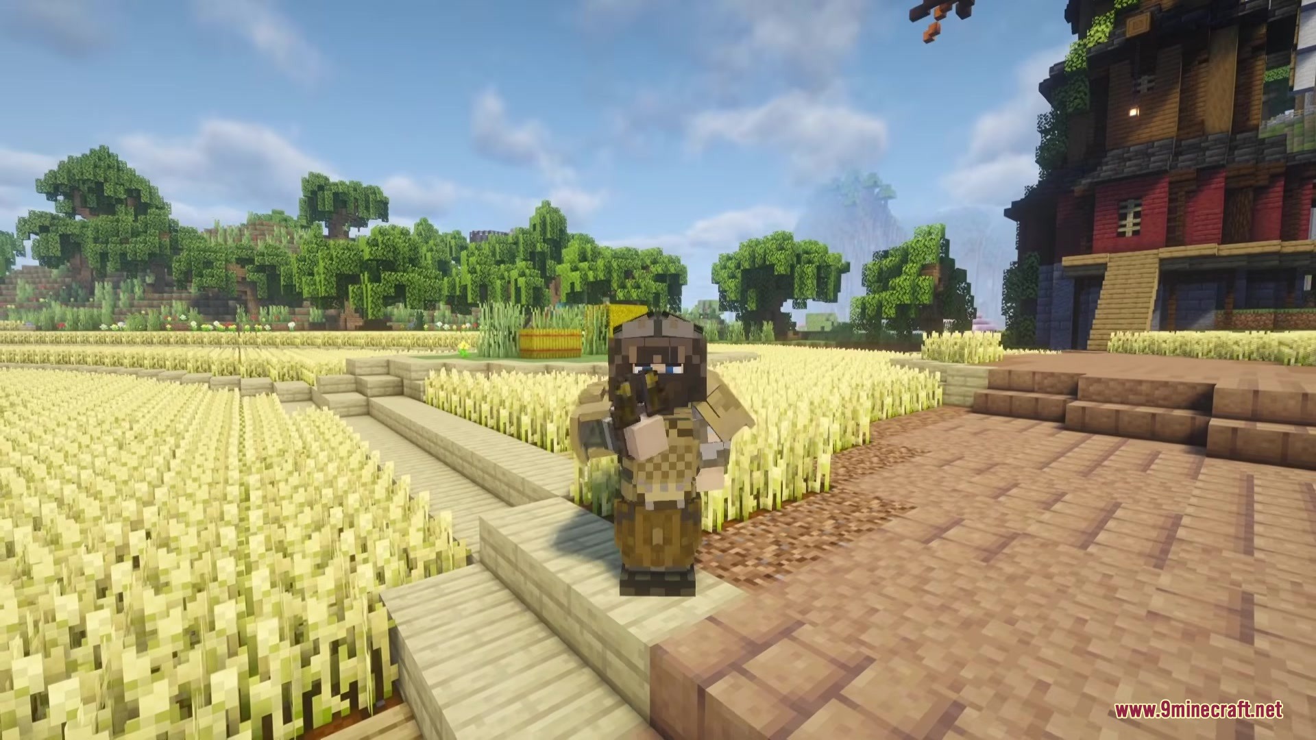 TACZ MORE LEVEL Mod Screenshot 6 A player wearing tactical armor holds a gun in a golden wheat field