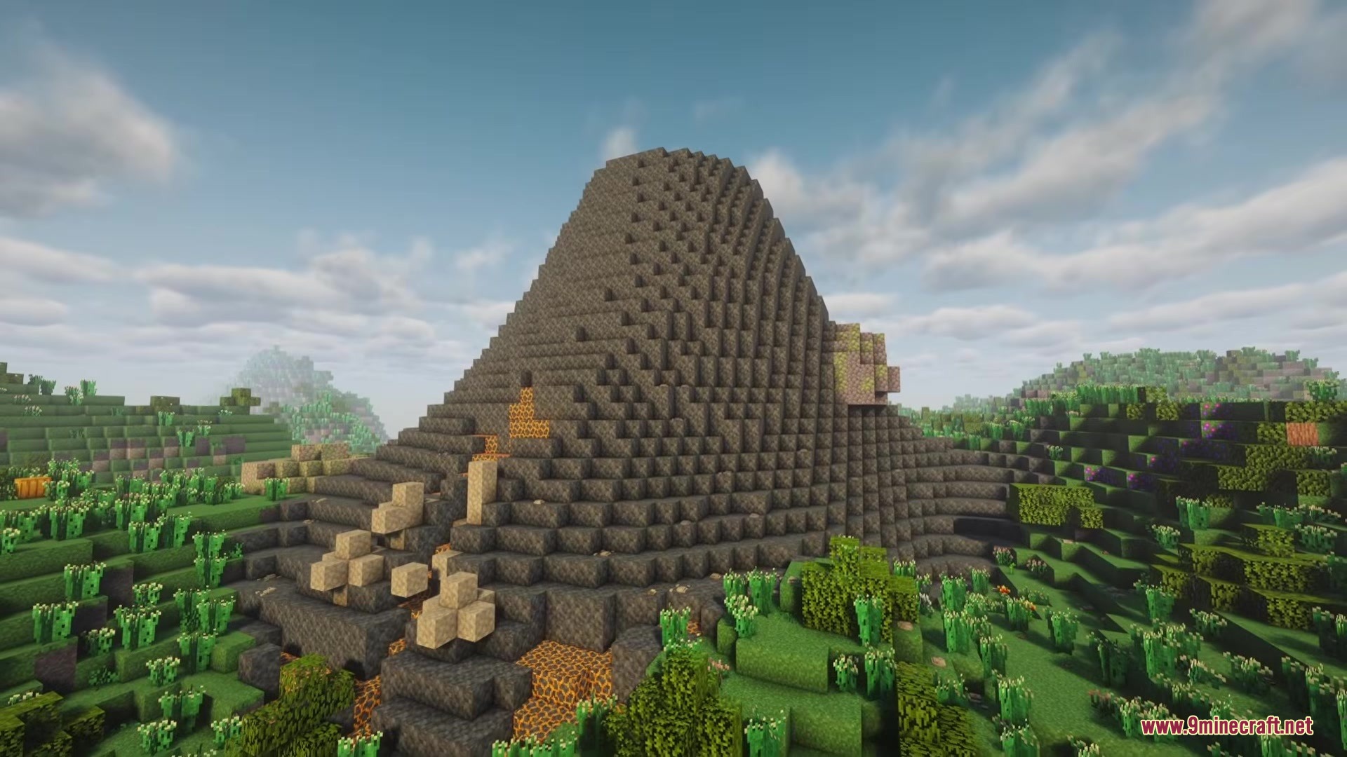A massive grey volcano structure with lava patches in a lush green biome
