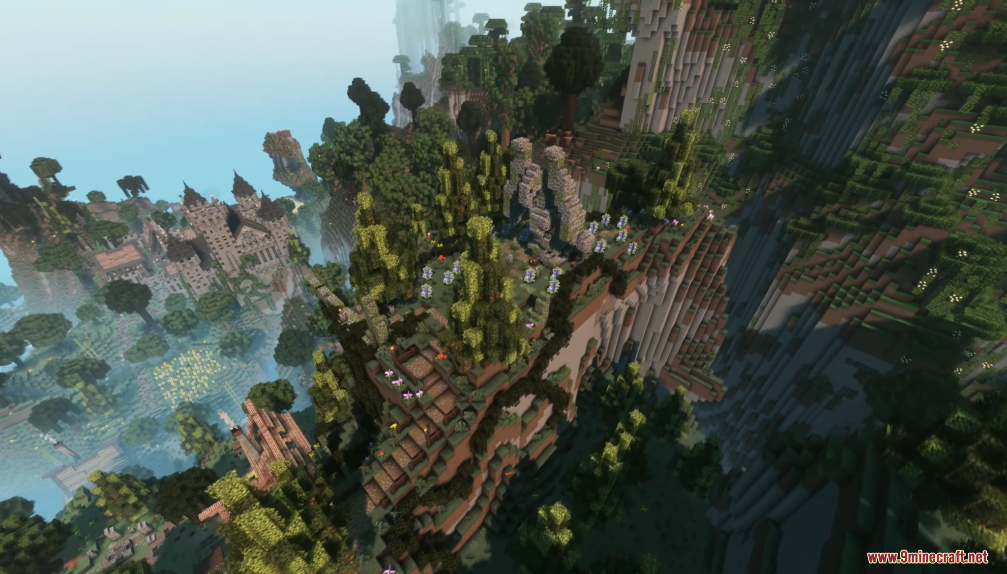 Aerial view of a large stone castle and village in a lush valley