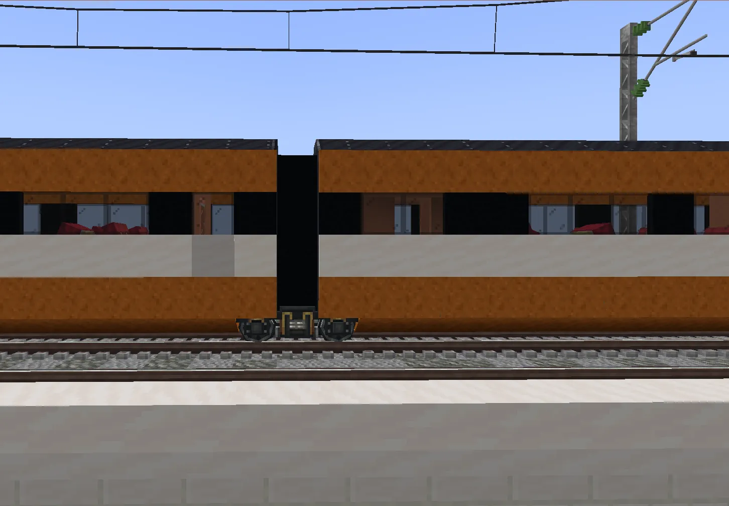 Close up of the wheels and connection between two orange train cars