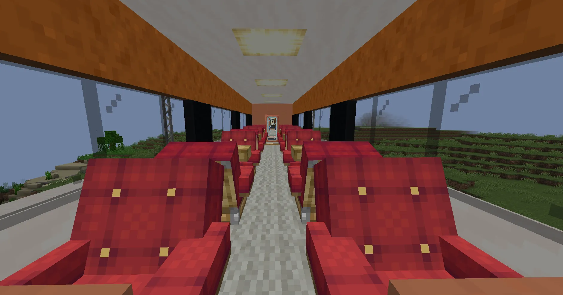 Modern train interior featuring rows of red passenger seats and wooden tables