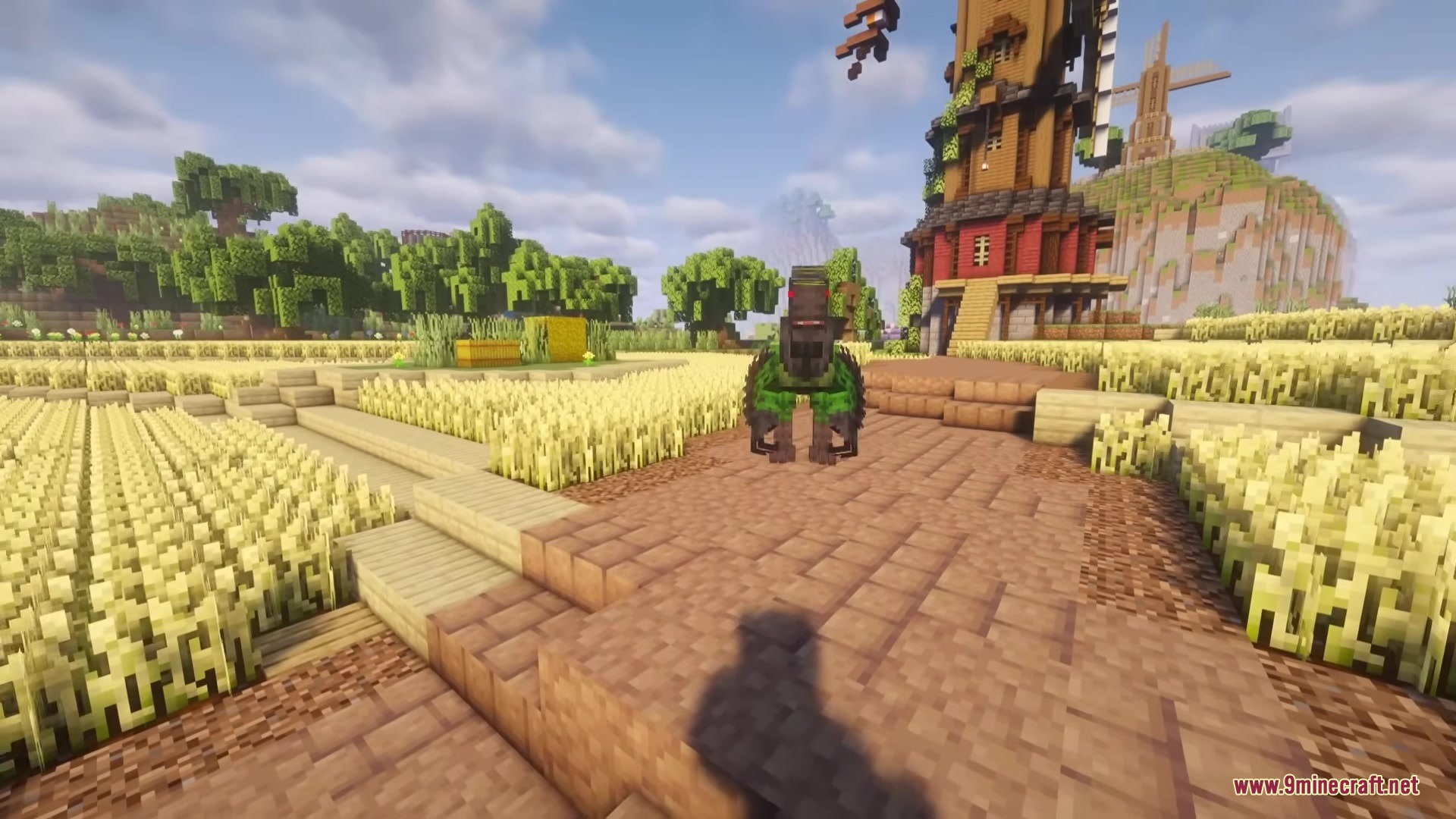 A green dinosaur stands on a path near a large windmill structure