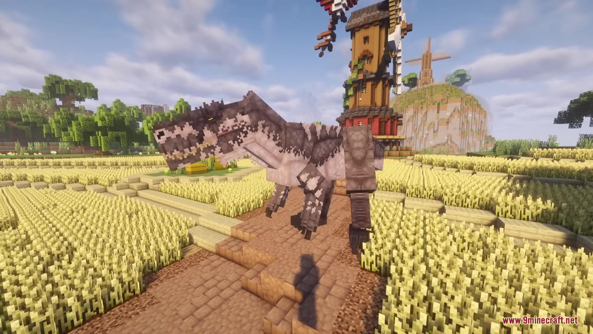 A massive Giganotosaurus stands in a golden wheat field near a tall windmill
