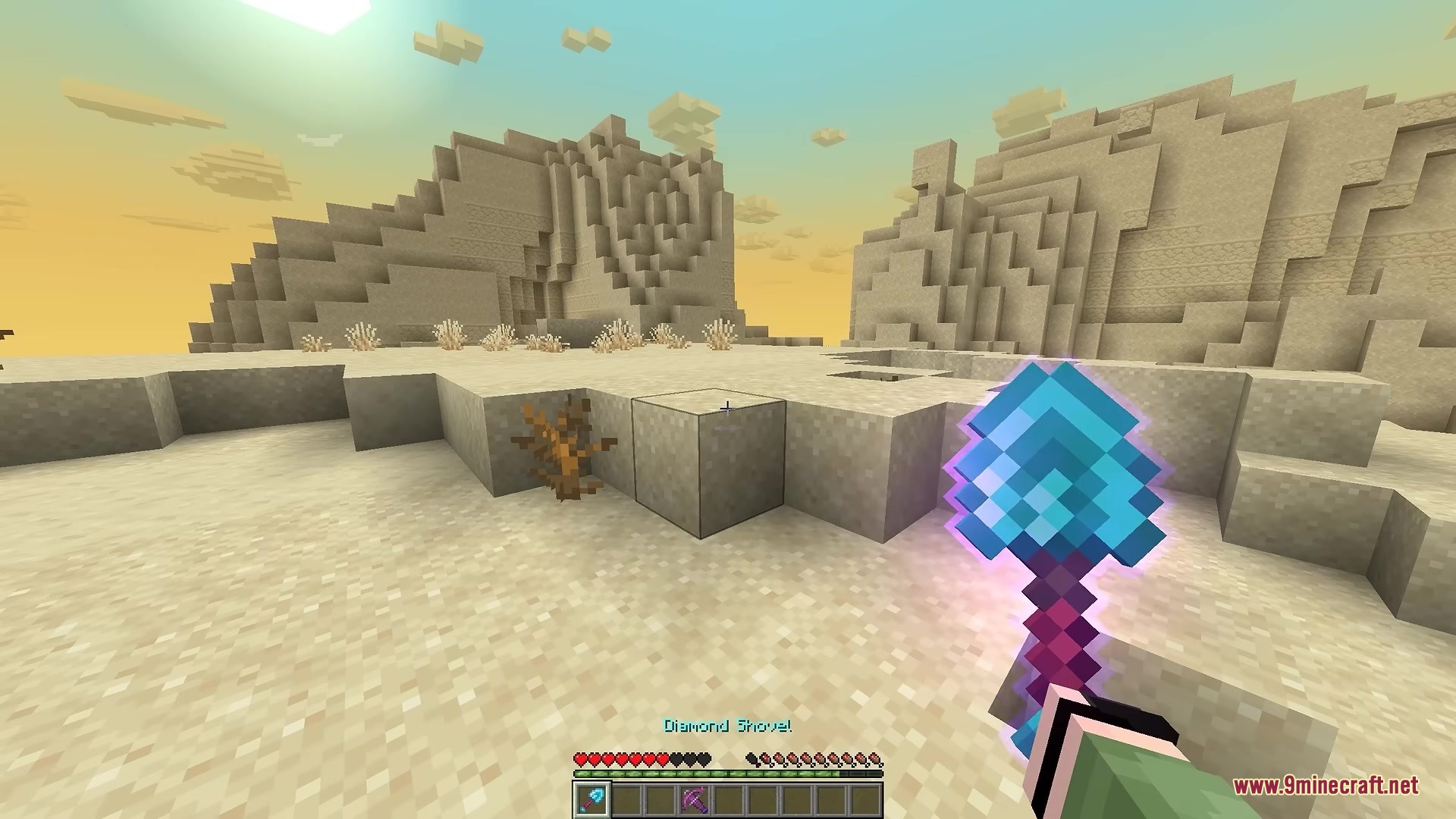 A player holds an enchanted diamond shovel in a vast desert biome