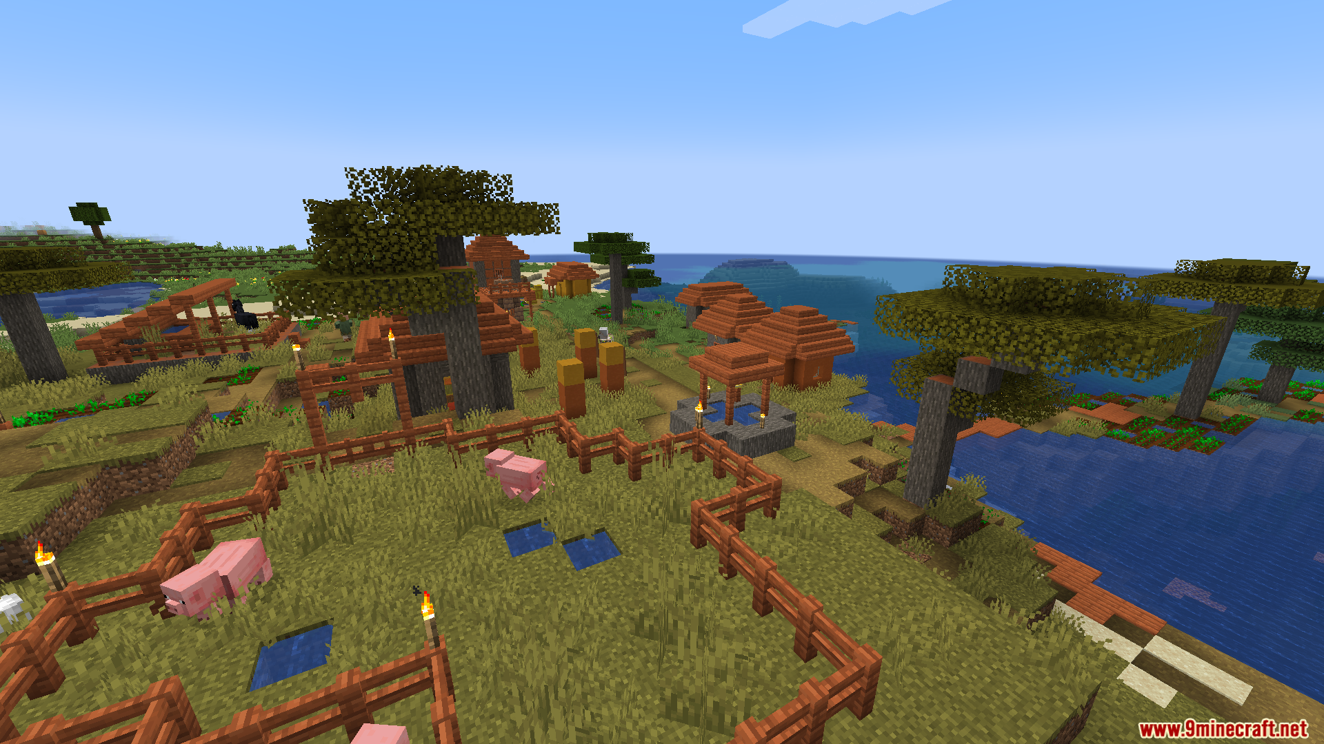 Villagers Plus PT BR Translation Resource Pack Screenshot 11 Pink pigs roaming inside a wooden enclosure within a scenic savanna village