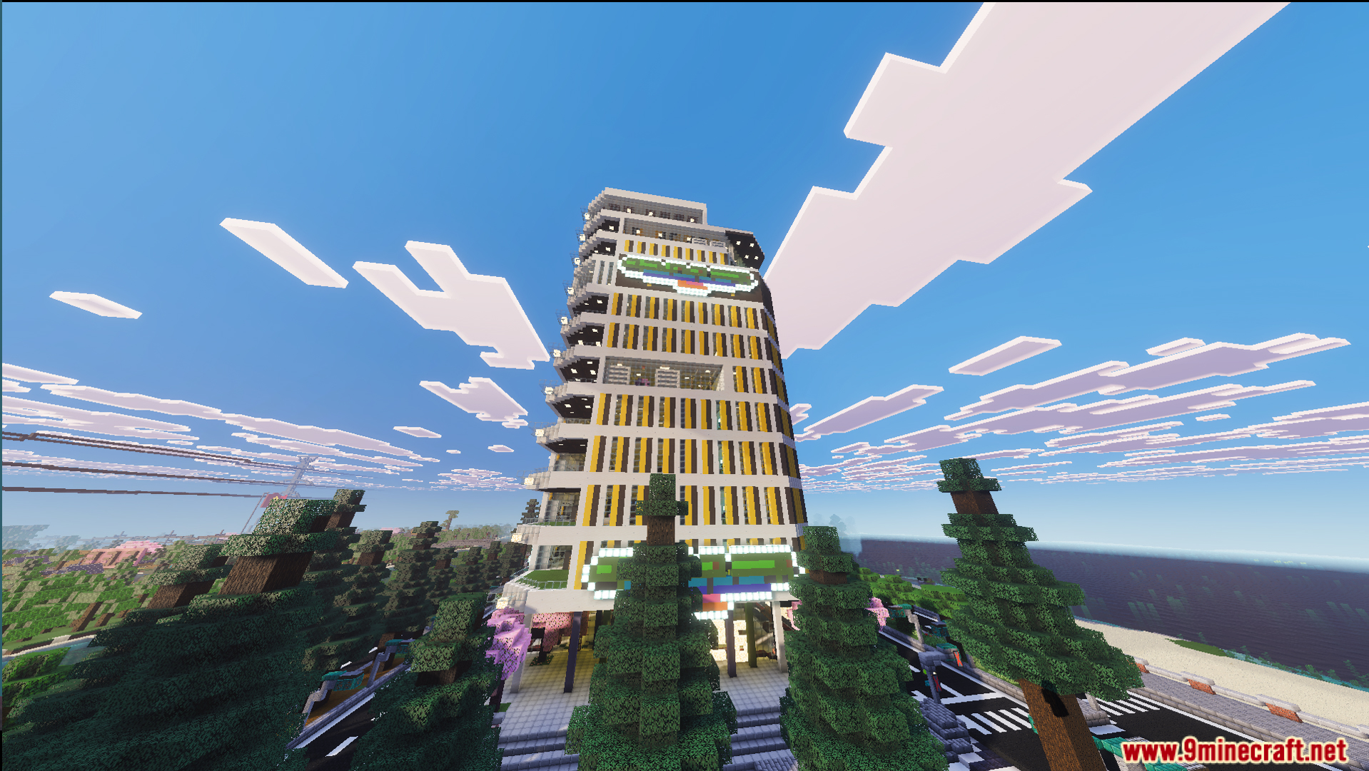 A tall modern building with yellow stripes stands amidst a lush pine forest