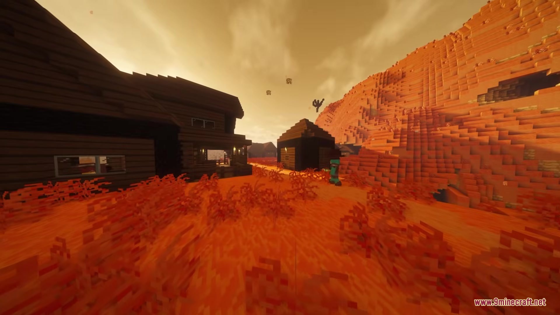 Wushima Mod Screenshot 2 Wooden houses and red bushes under a hazy orange desert sky