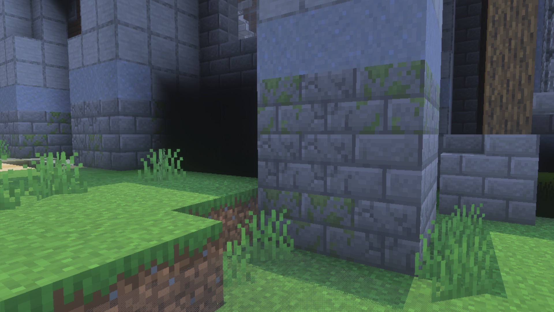 Close up of mossy stone bricks and grass blocks in a Minecraft world