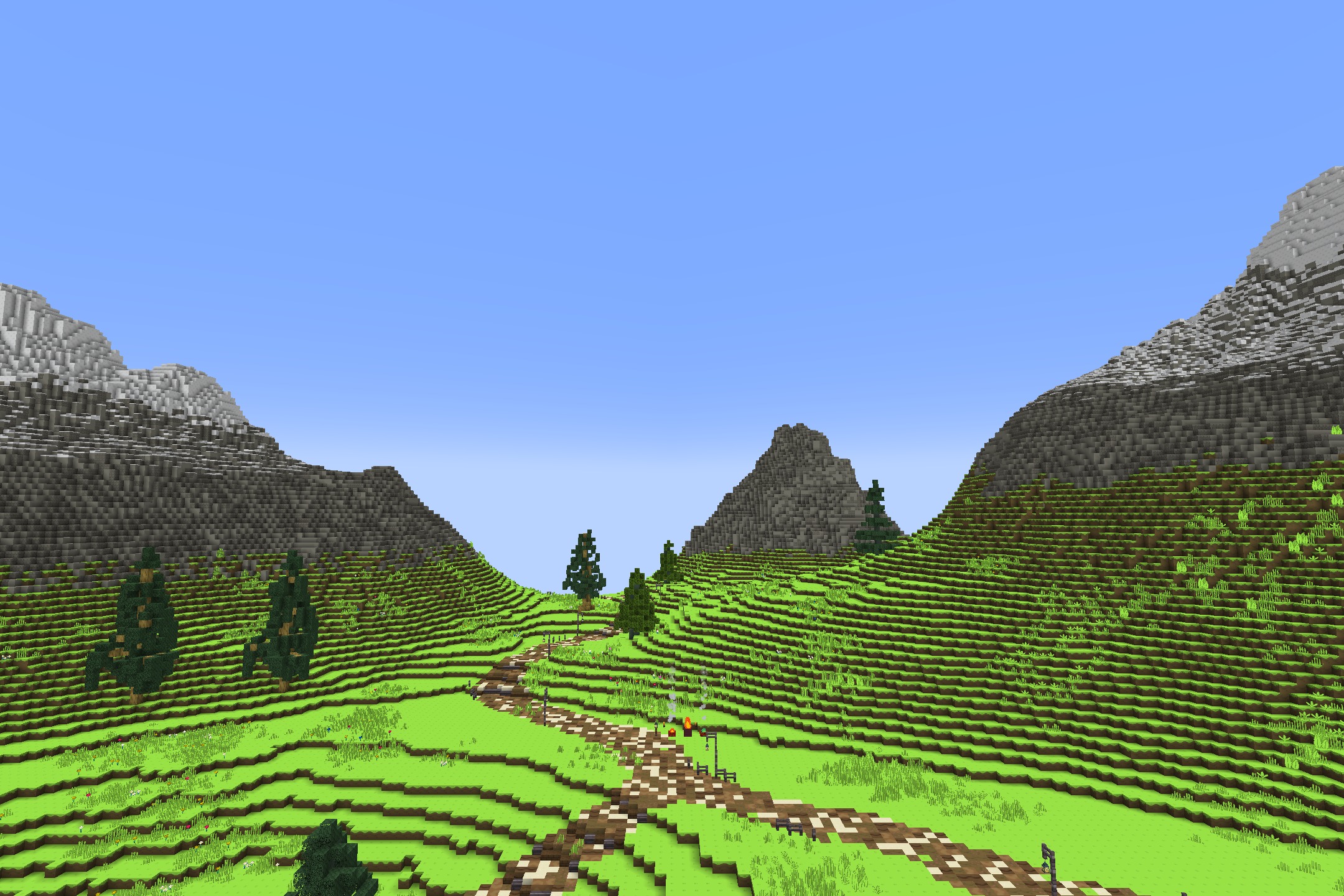 A winding dirt path leads through vibrant green hills toward distant blocky mountains