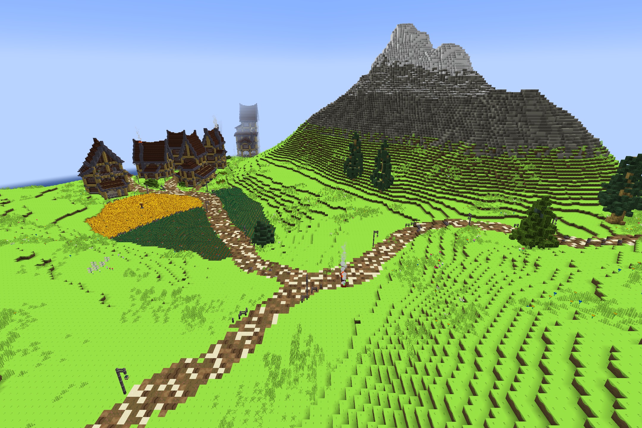 A small village with cartoonish houses sits next to a golden field