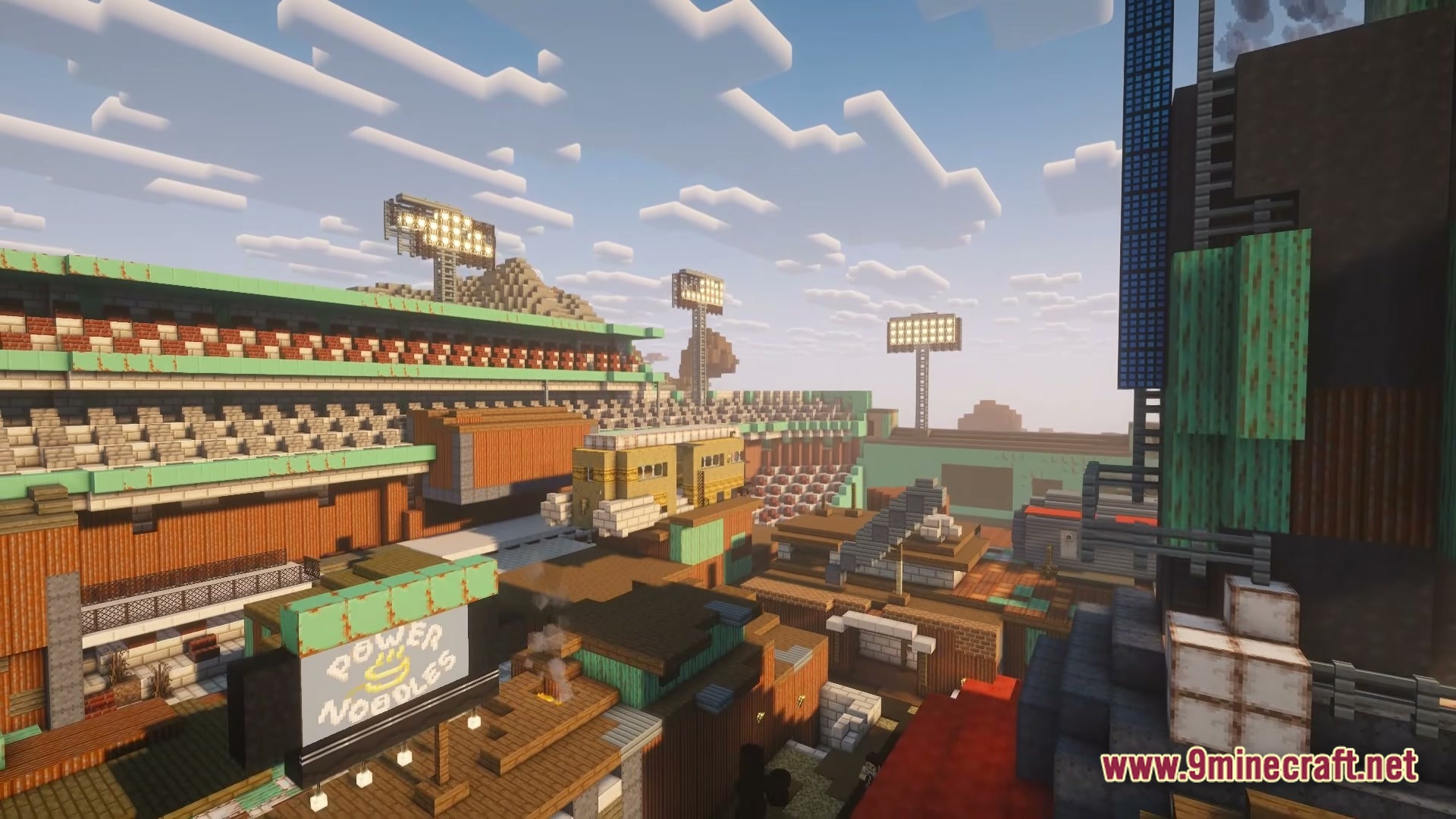 After The Nukes Modpack Screenshot 4 A post-apocalyptic settlement built within the ruins of a large sports stadium under a cloudy sky