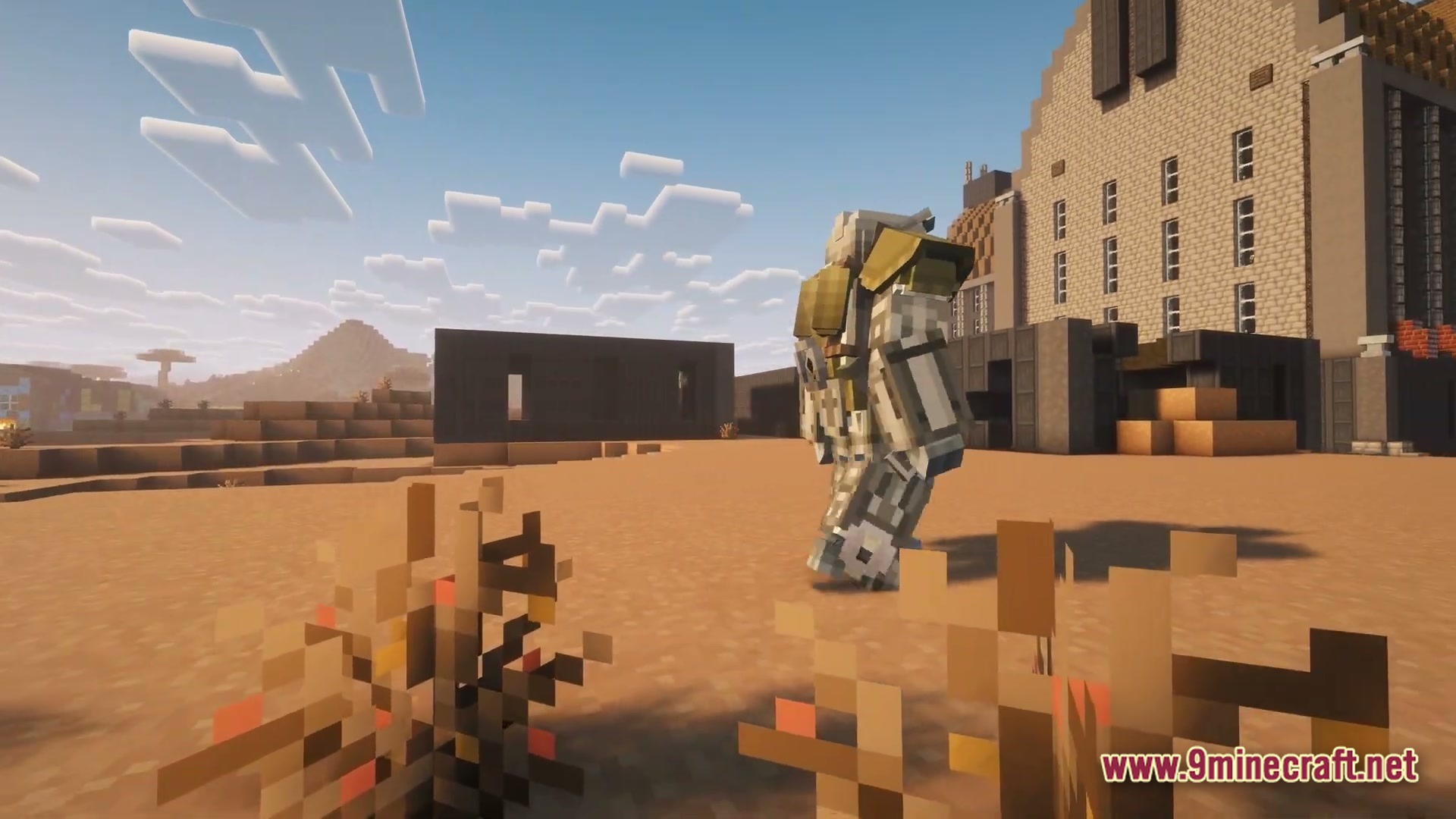 After The Nukes Modpack Screenshot 6 A player wearing heavy power armor walks through a desert wasteland near abandoned industrial buildings
