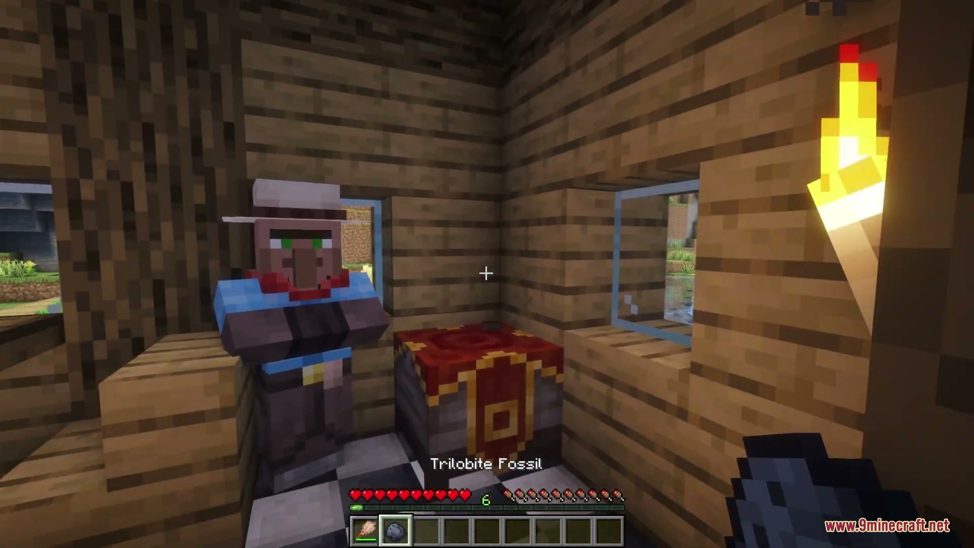 A player holds a trilobite fossil item while standing near a custom villager