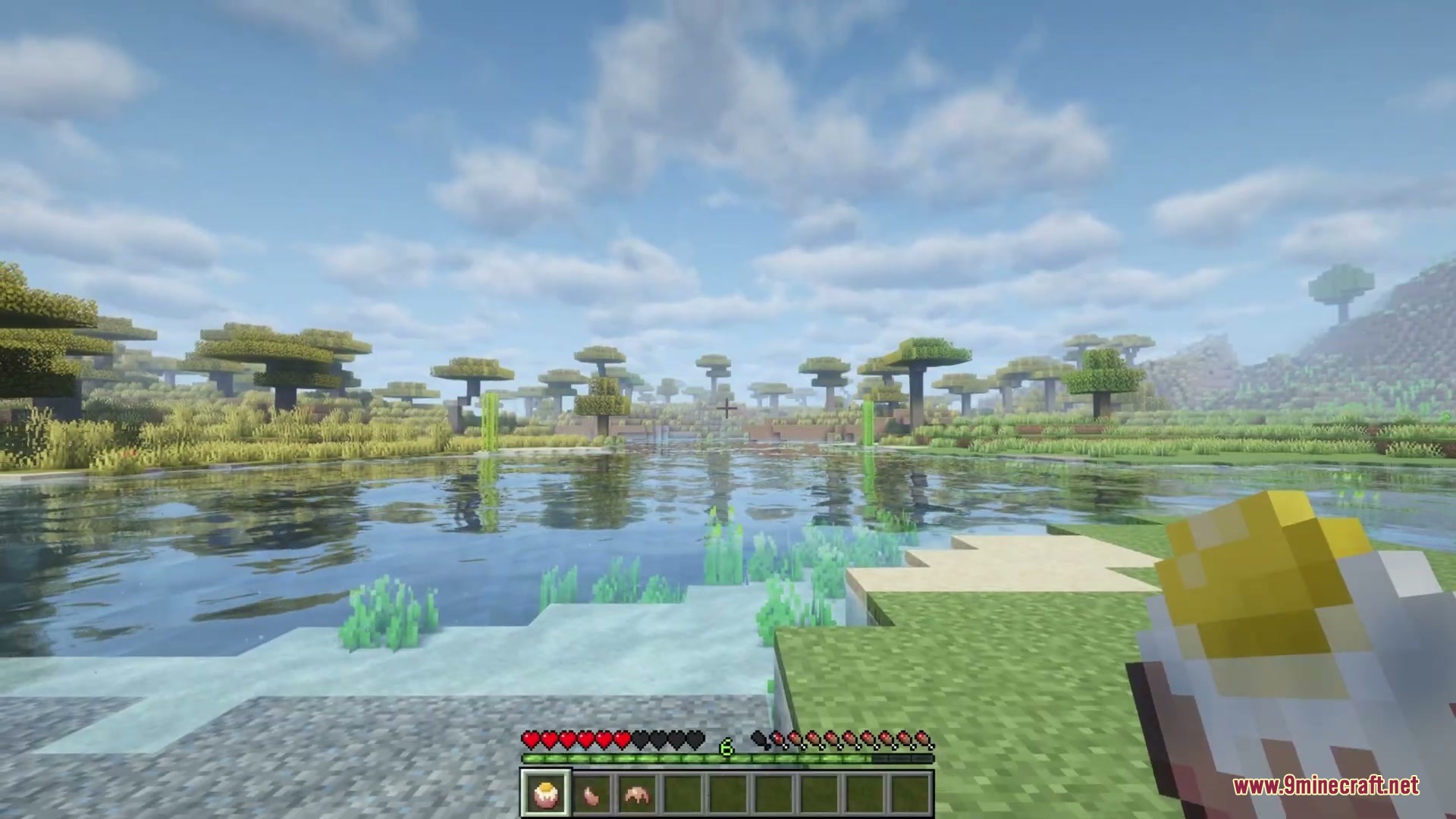 Player holding a food item while looking at a scenic prehistoric lake landscape