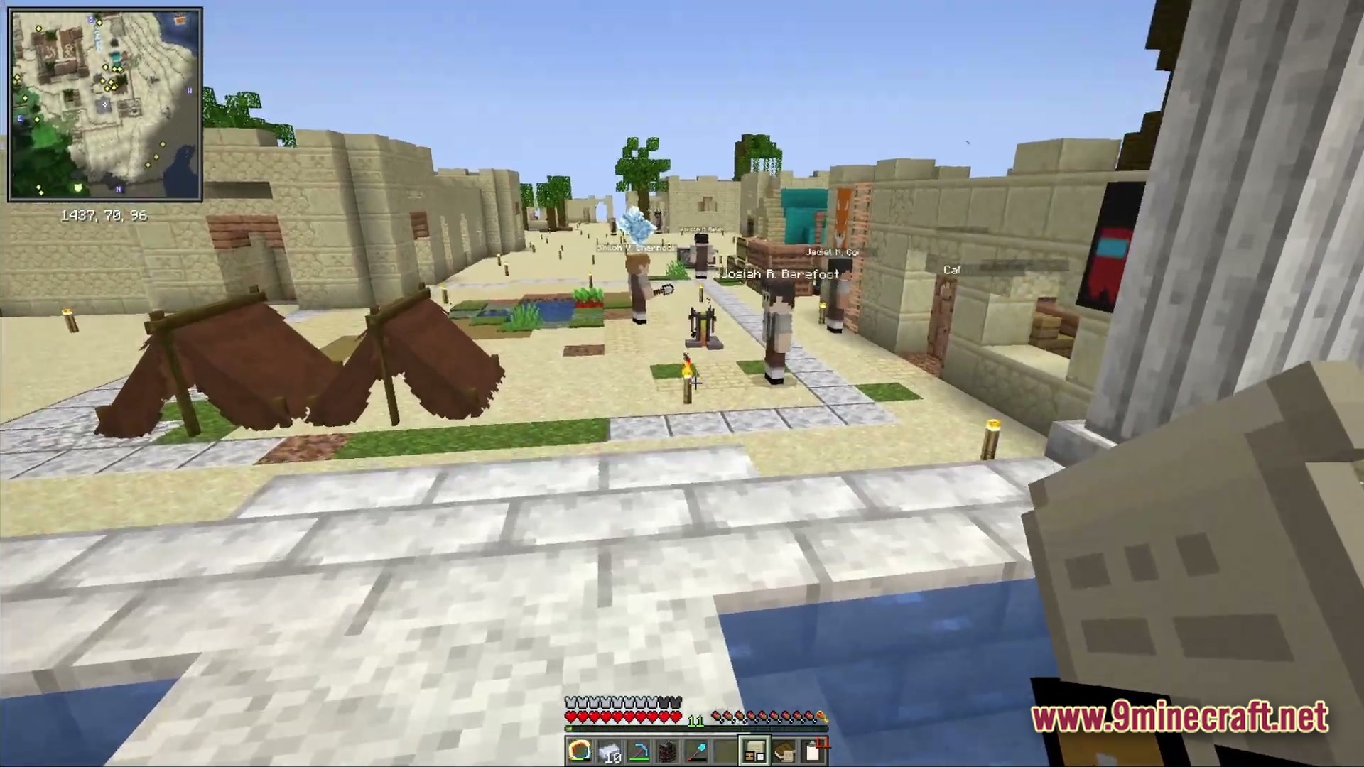 Ancient Kingdoms 3 Modpack Screenshot 2 Several NPCs stand near sandstone buildings and tents in a desert village settlement