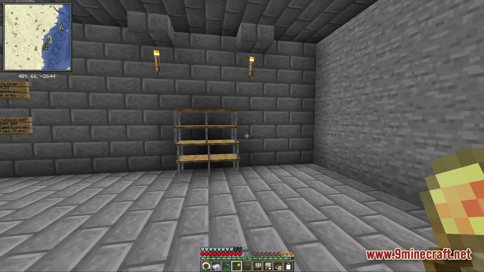Ancient Kingdoms 3 Modpack Screenshot 5 A stone brick room featuring empty wooden shelves, wall torches, and signs near a corner