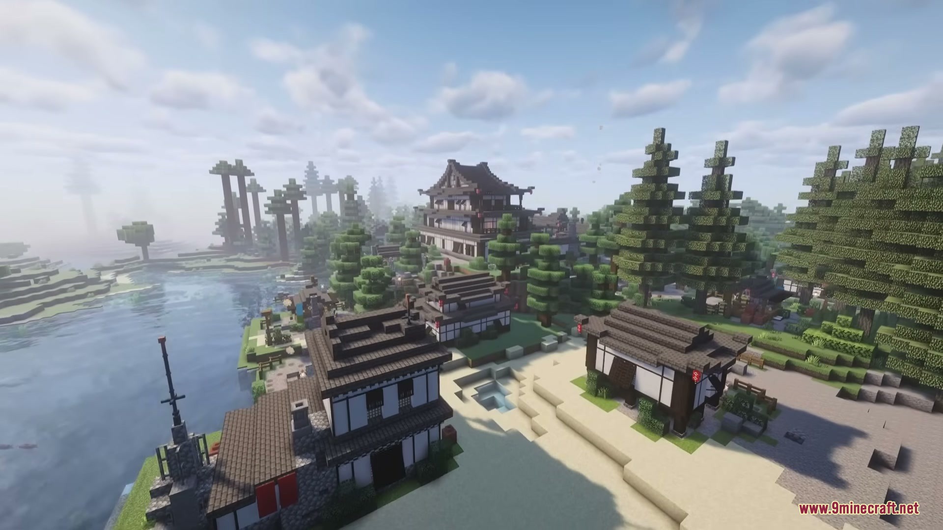 Traditional Japanese buildings nestled among pine trees next to a large lake