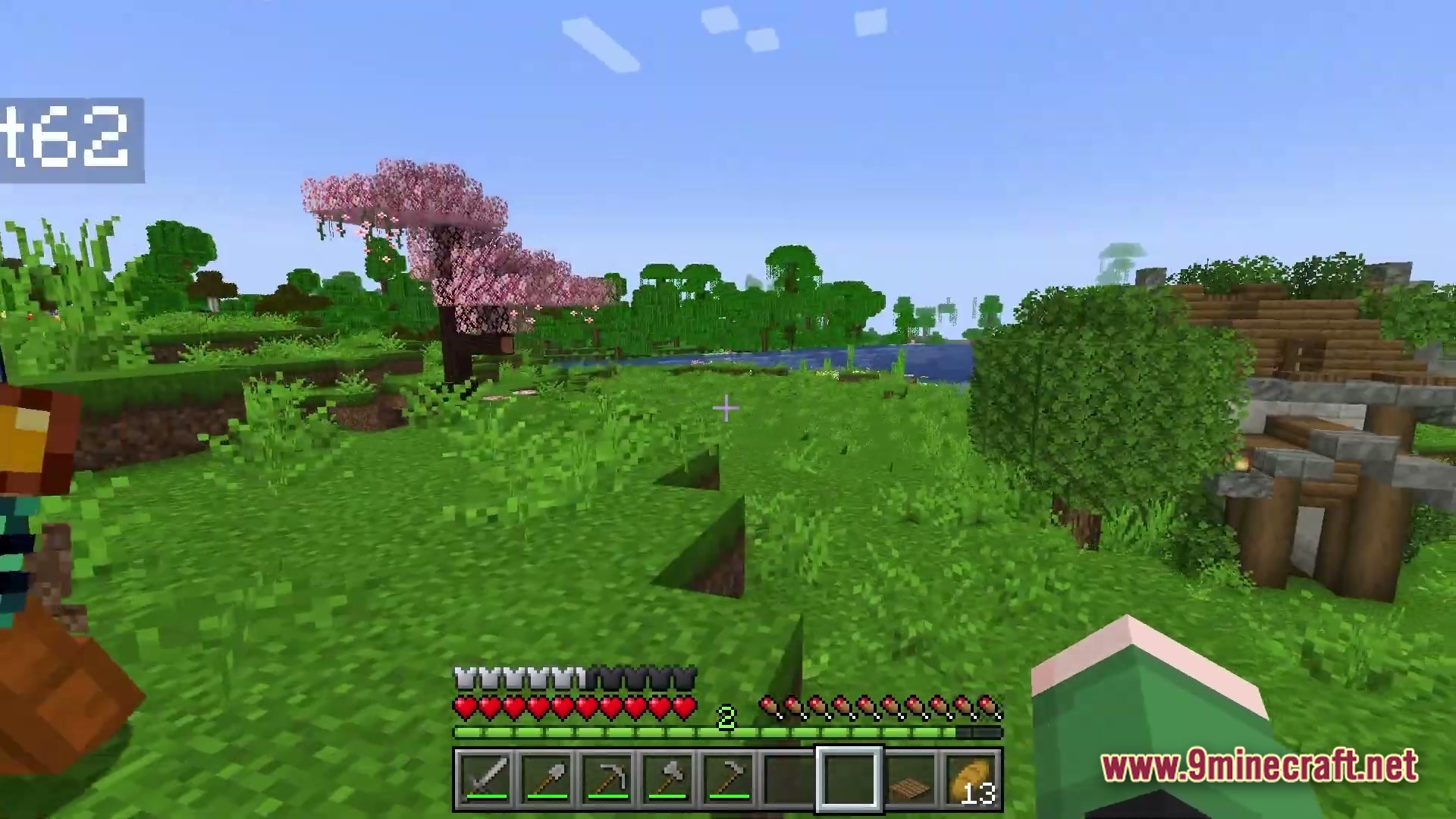 Arcanum Land Modpack Screenshot 4 A player stands in a grassy biome featuring a cherry blossom tree and a wooden structure