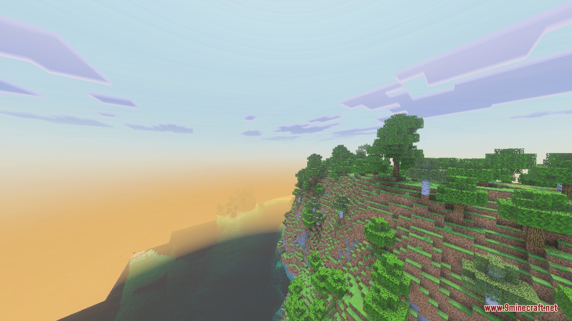A steep cliff with green trees overlooking the ocean during a soft sunset