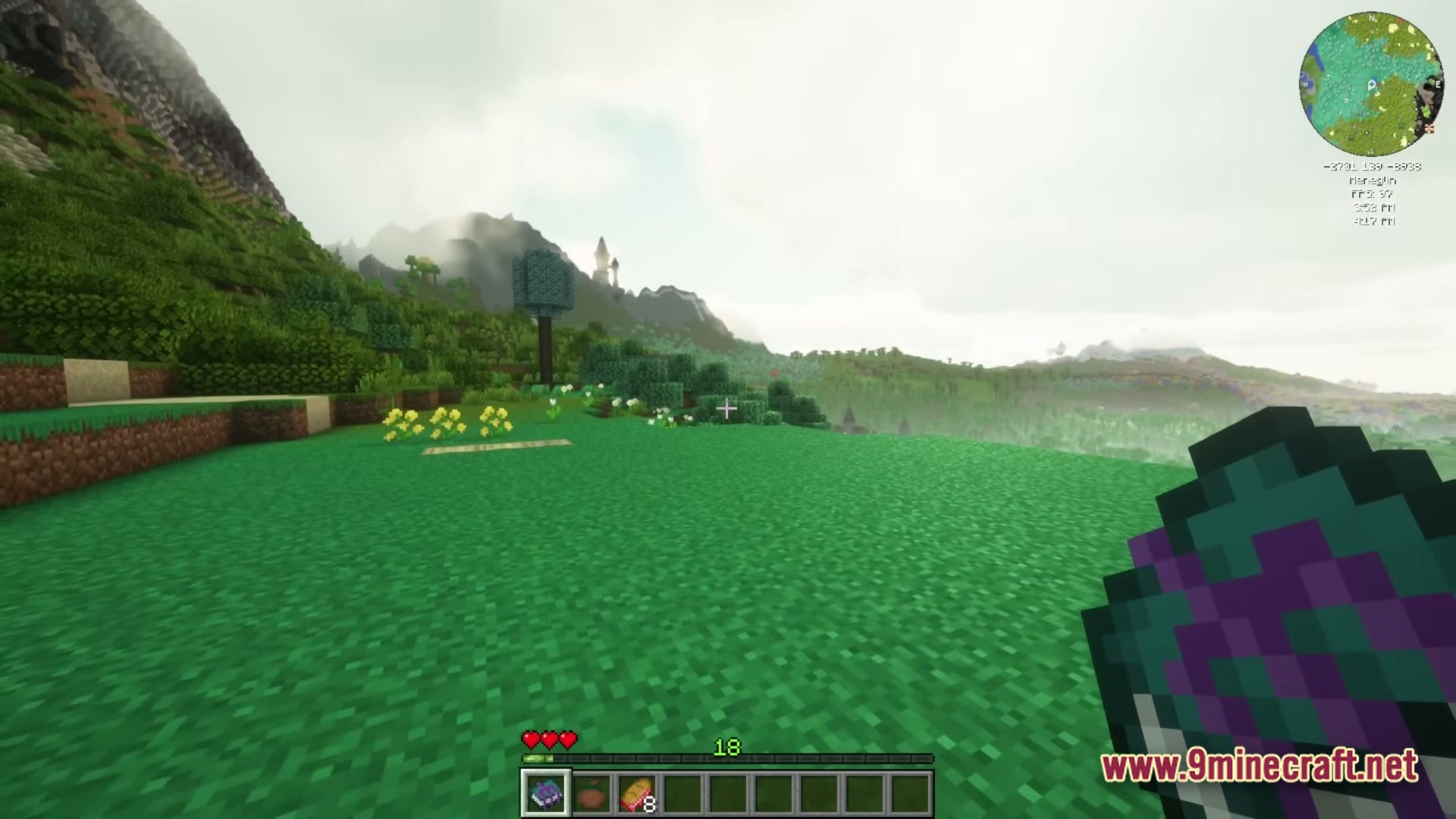 A player holds a purple book while overlooking a hilly landscape with custom trees and distant structures
