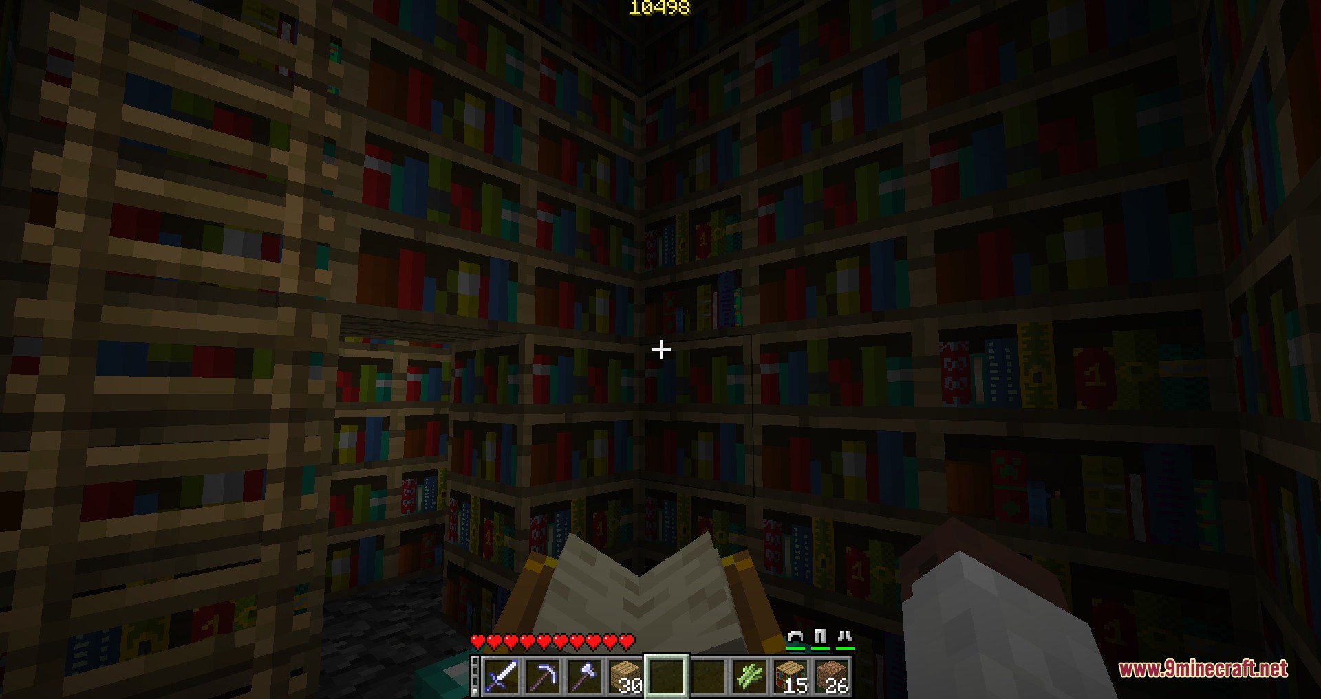 Better with Enchanting Mod Screenshot 7 A player holding a book while exploring a dark library filled with bookshelves