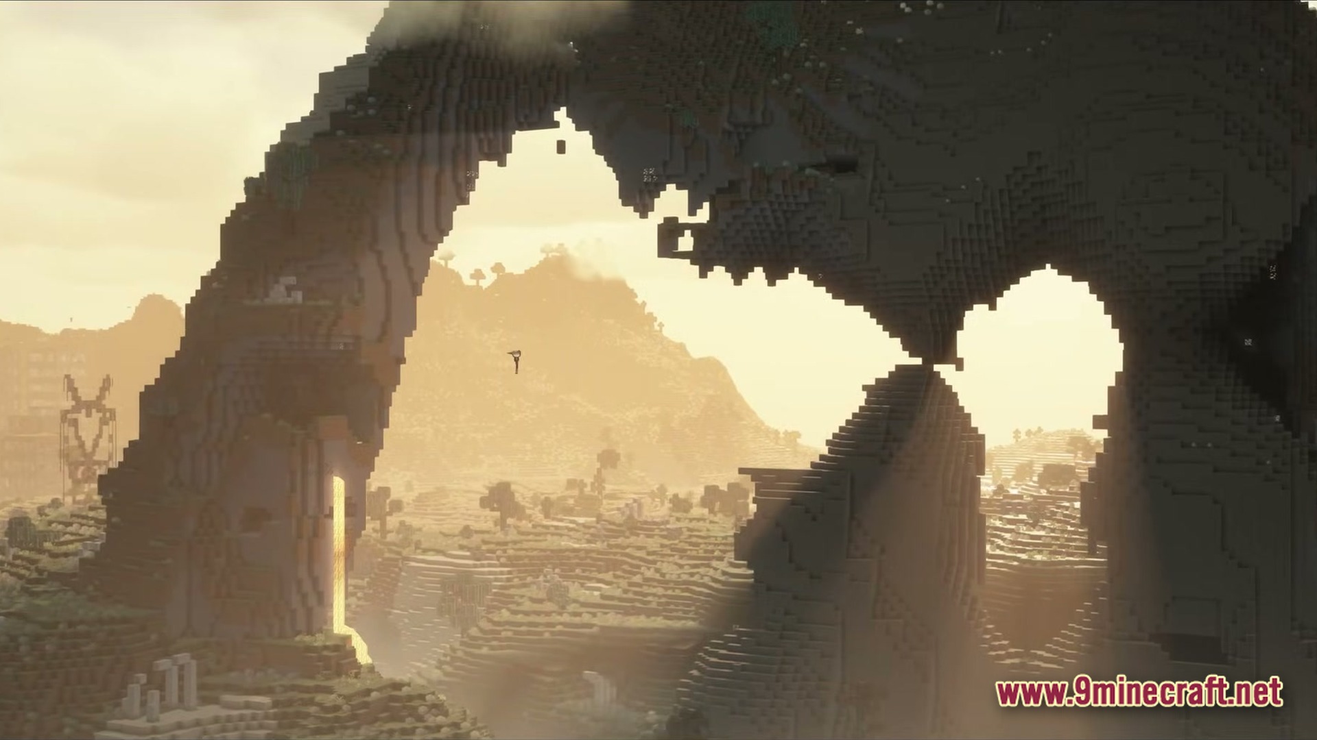 A large stone archway overlooks a desolate, foggy wasteland with distant mountains and industrial structures