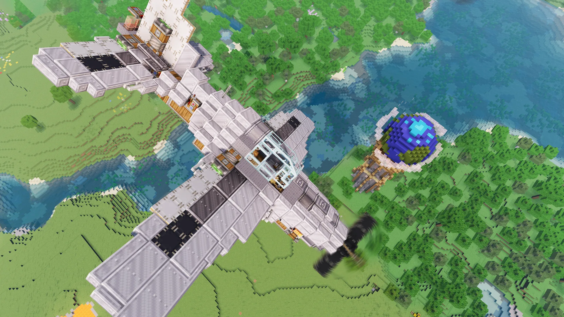 A large grey Bluejay fighter plane flying high above a lush forest landscape