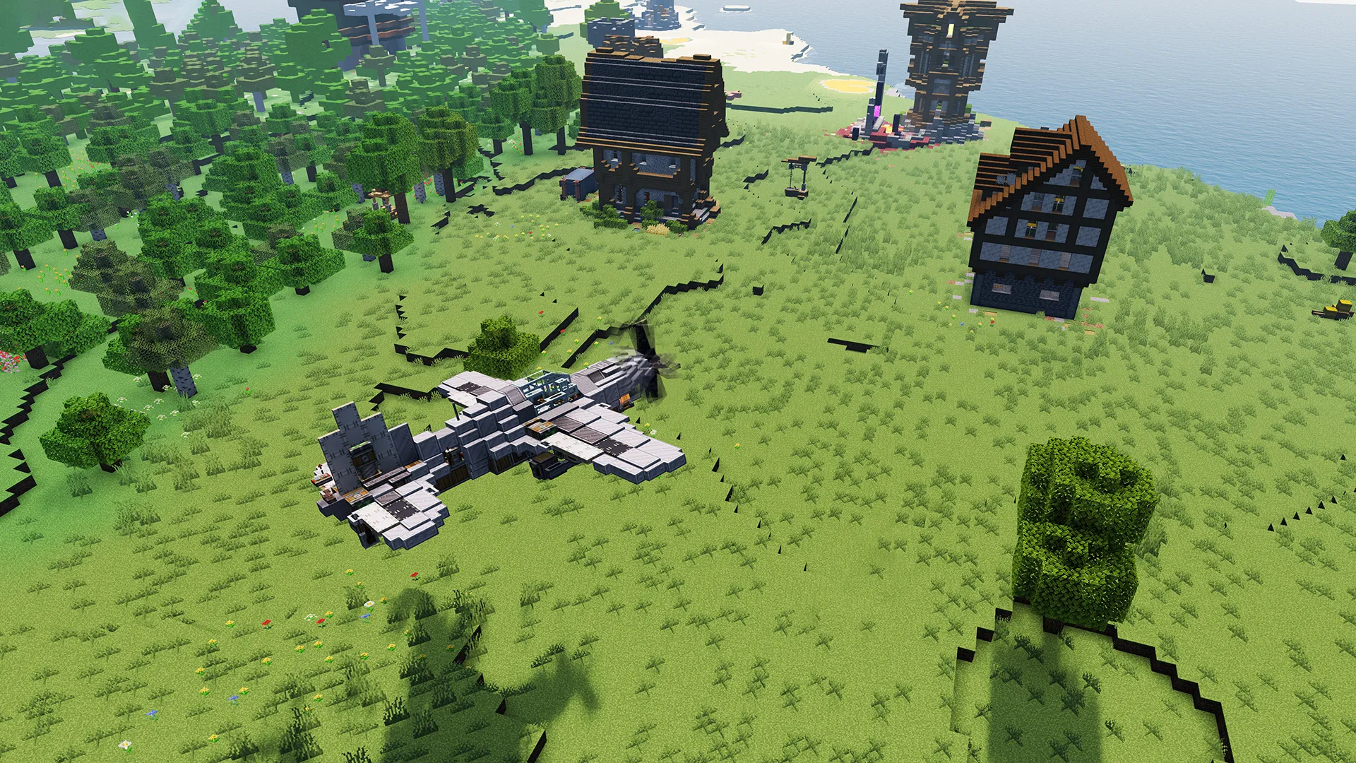 A grey fighter plane flying low over a grassy field with several buildings