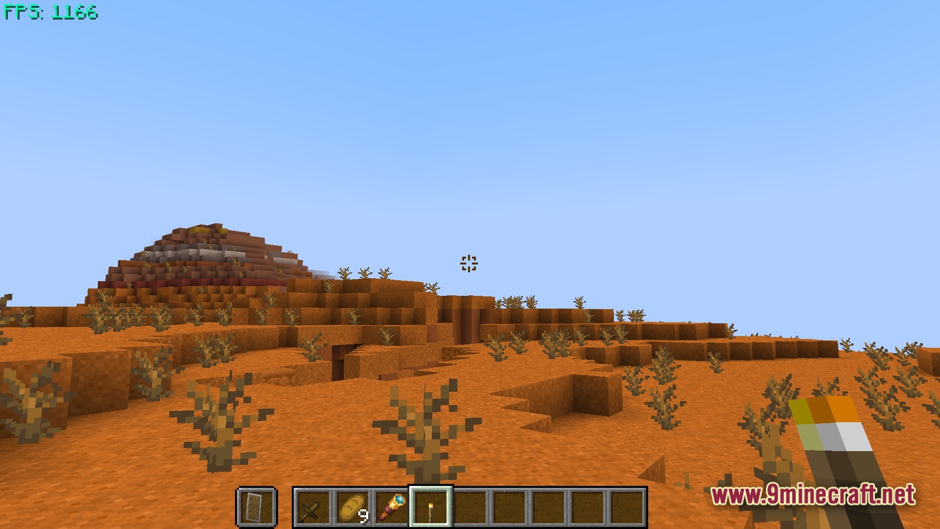 Boosted FPS Performance Optimized Modpack Screenshot 10 A first-person view of a player holding a torch in a desert badlands biome with high FPS